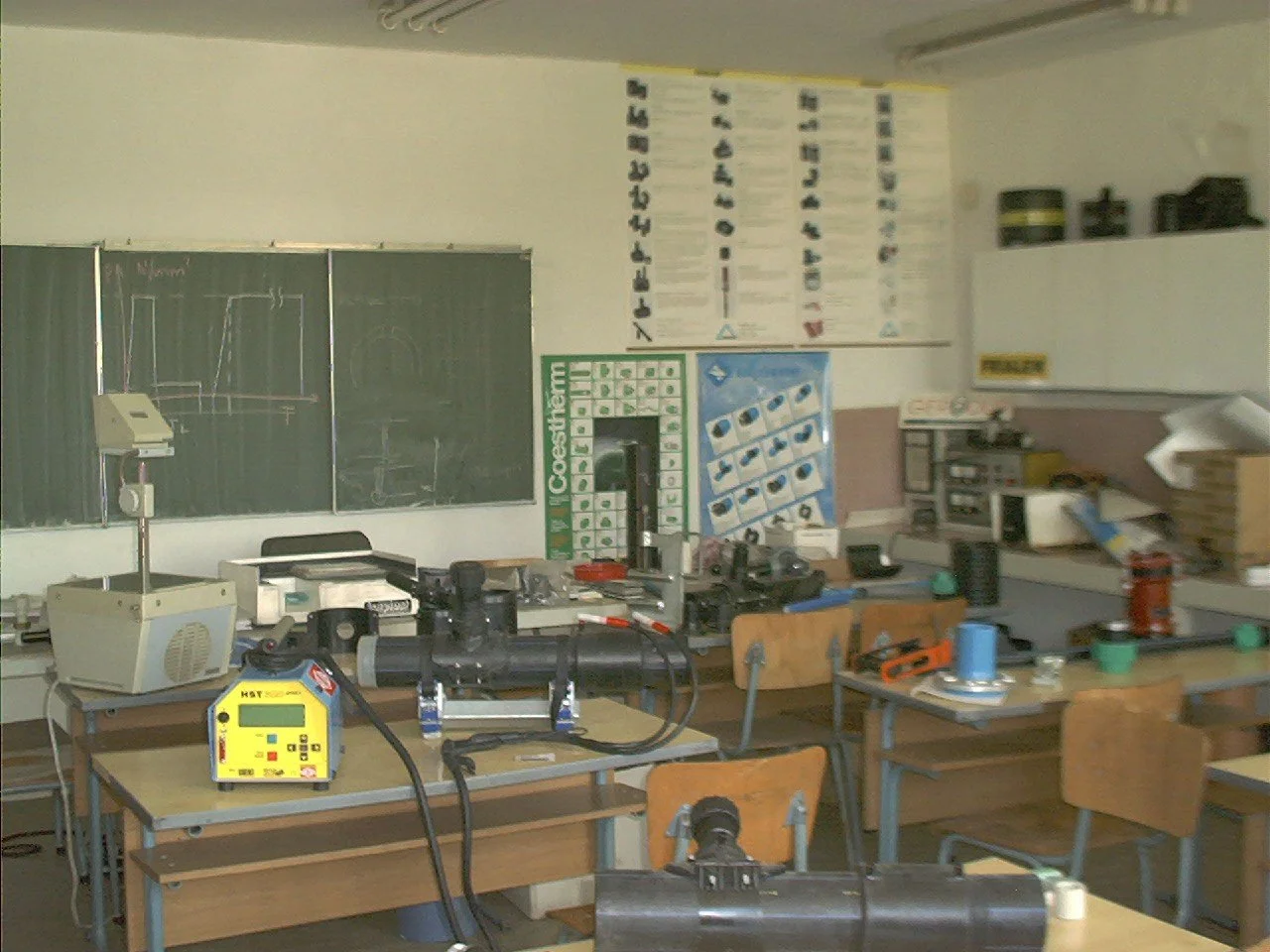 Science classroom with blackboards, lab equipment, and desks with tools and materials for experiments.