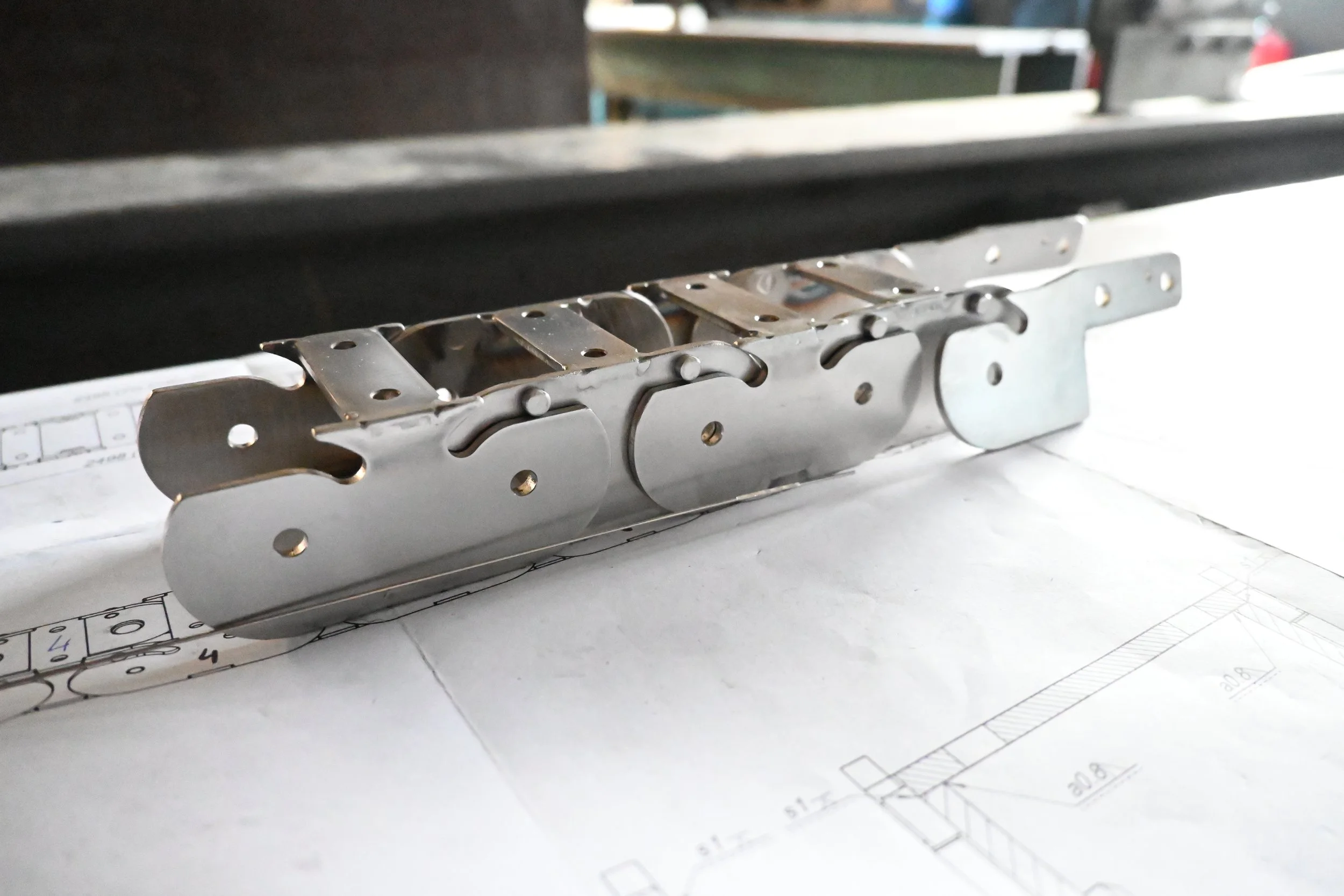 A metal mechanical part placed on engineering blueprints.