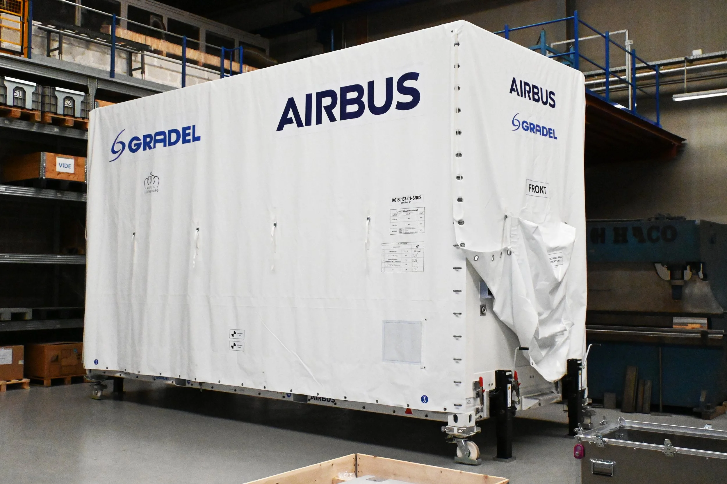 Large white aircraft engine testing chamber with 'AIRBUS' and 'GRADEL' logos, situated in an industrial warehouse.