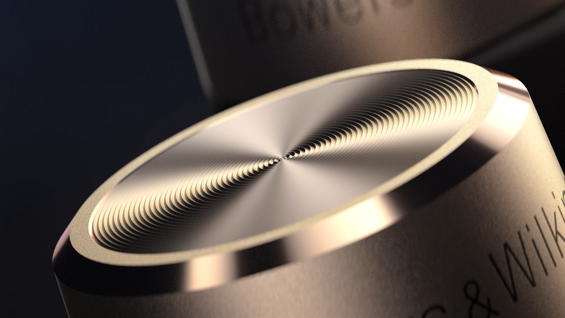 A close-up of a metallic, circular dial with ridges, part of an electronic device. Part of the device's surface and some text are visible.