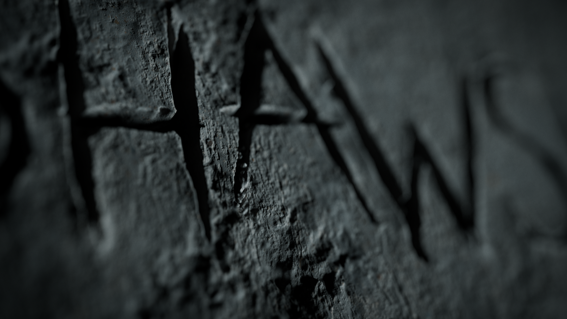 Close-up of a rough, dark gray stone wall with carved or engraved symbols or letters.
