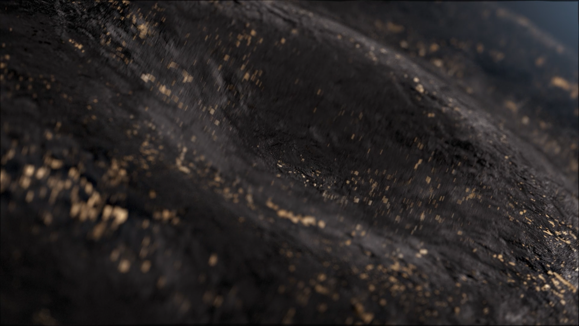 Close-up of a dark surface with scattered gold specks and a central hole, resembling a piece of black fabric or material with metallic accents.