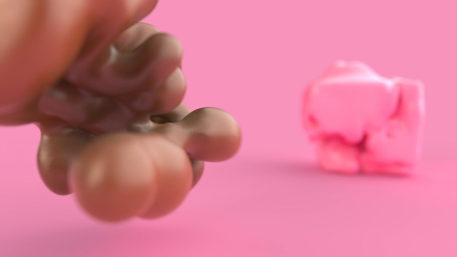 Close-up of a person's hand holding a small pink object against a pink background, with a pink cookie cutter in the shape of a pig in the distance.