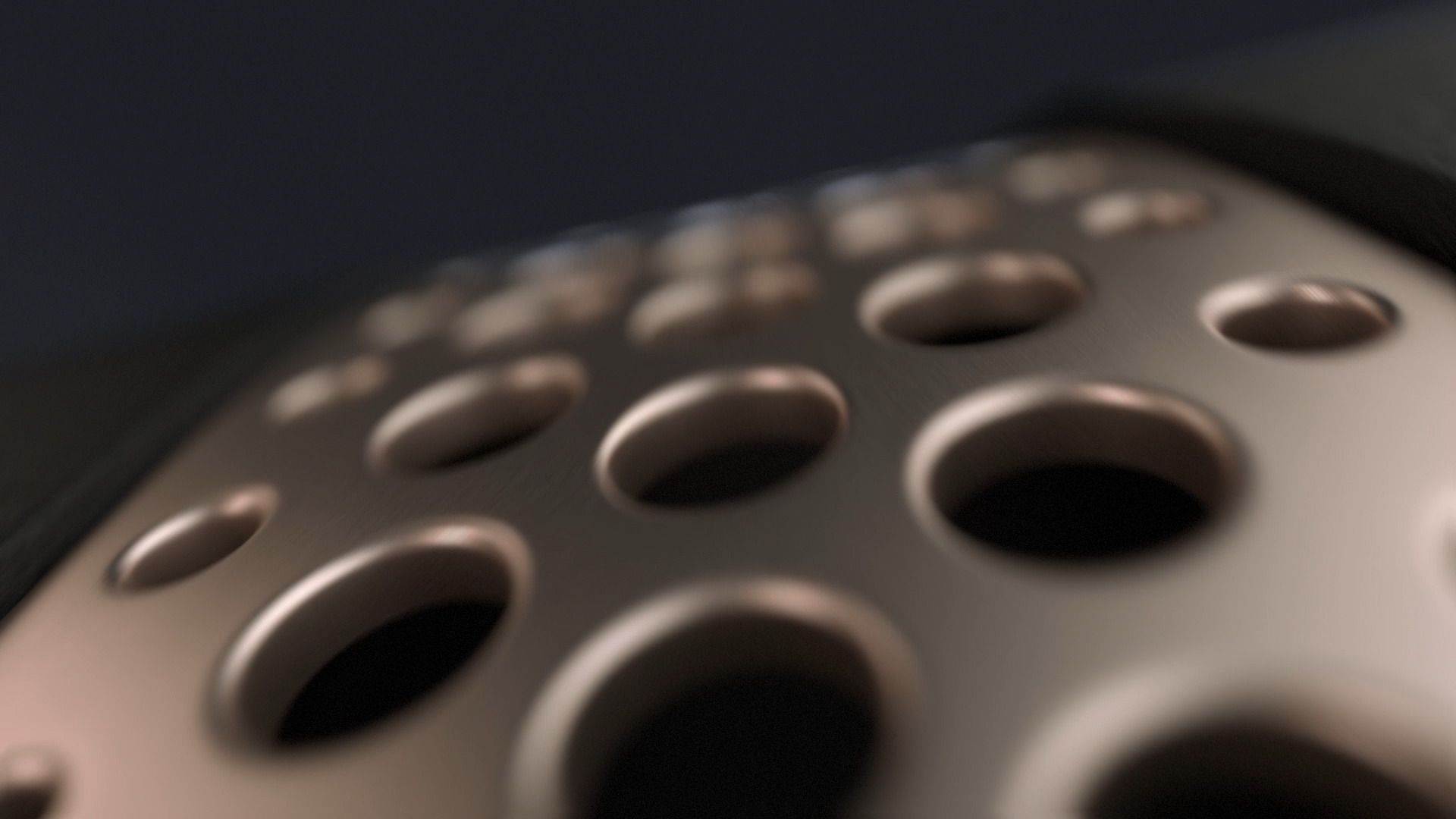 Close-up of a metallic object with circular holes, possibly part of a vent or speaker grille, with a blurred background.