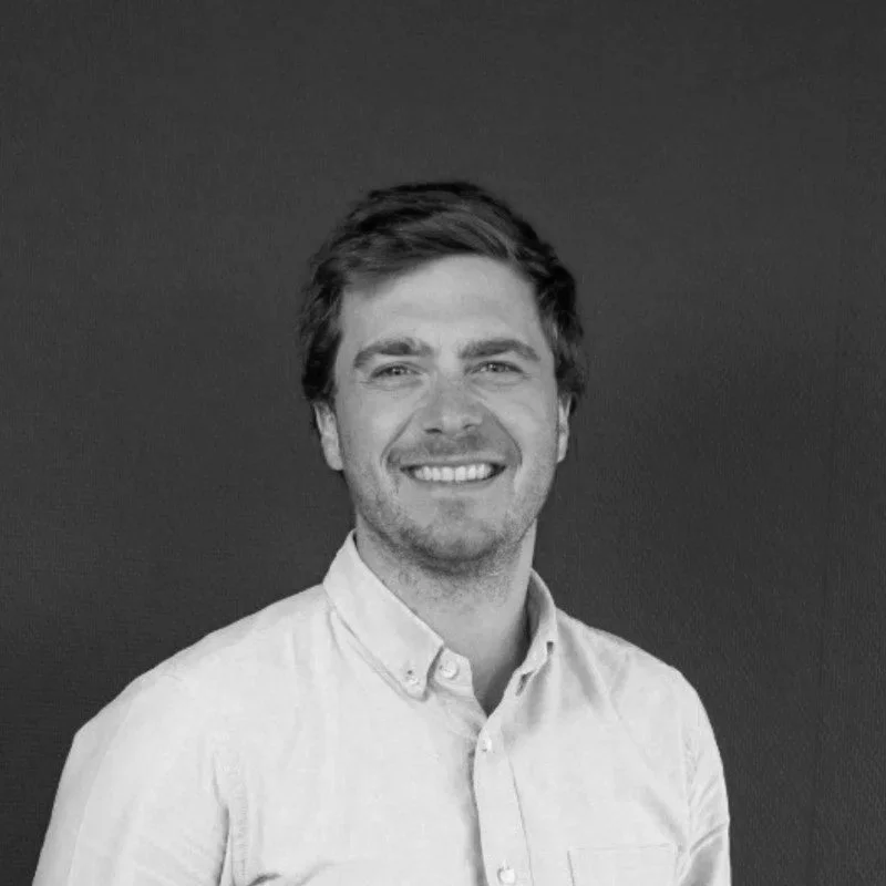 Portrait en noir et blanc d'un homme souriant portant une chemise claire.
