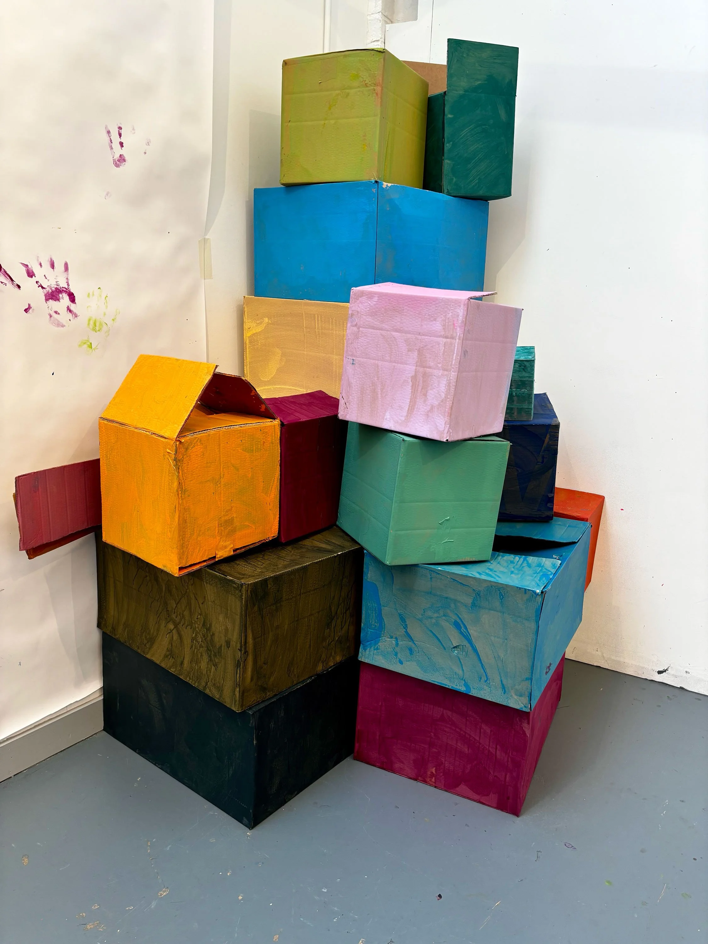 Stacked colorful cardboard boxes painted with bright colors in an art installation.