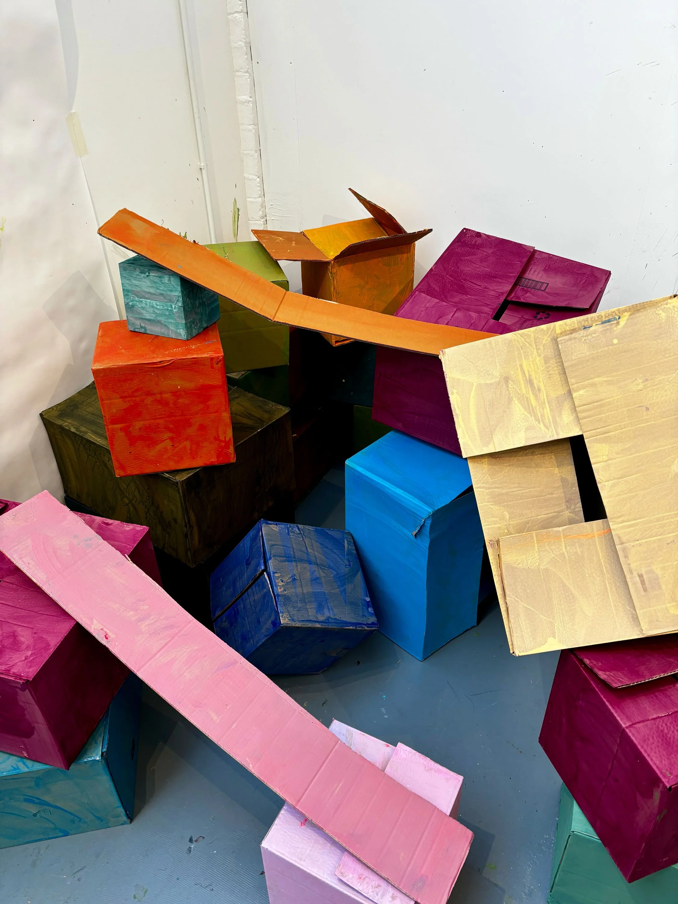 Colorful painted cardboard boxes and long rectangular pieces stacked together.