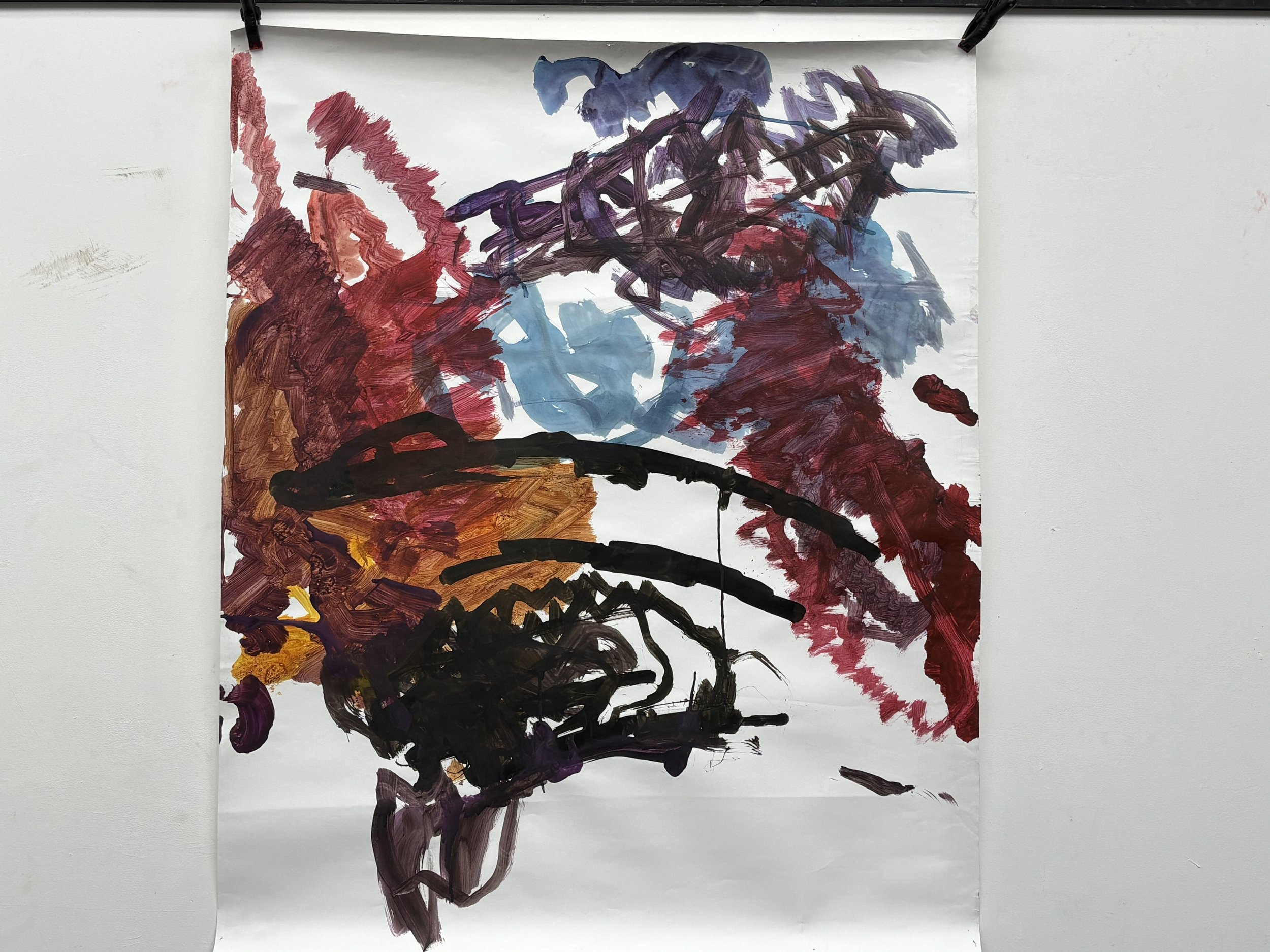 Abstract painting with bold, dark strokes and splashes of red, purple, blue, and black on white paper.