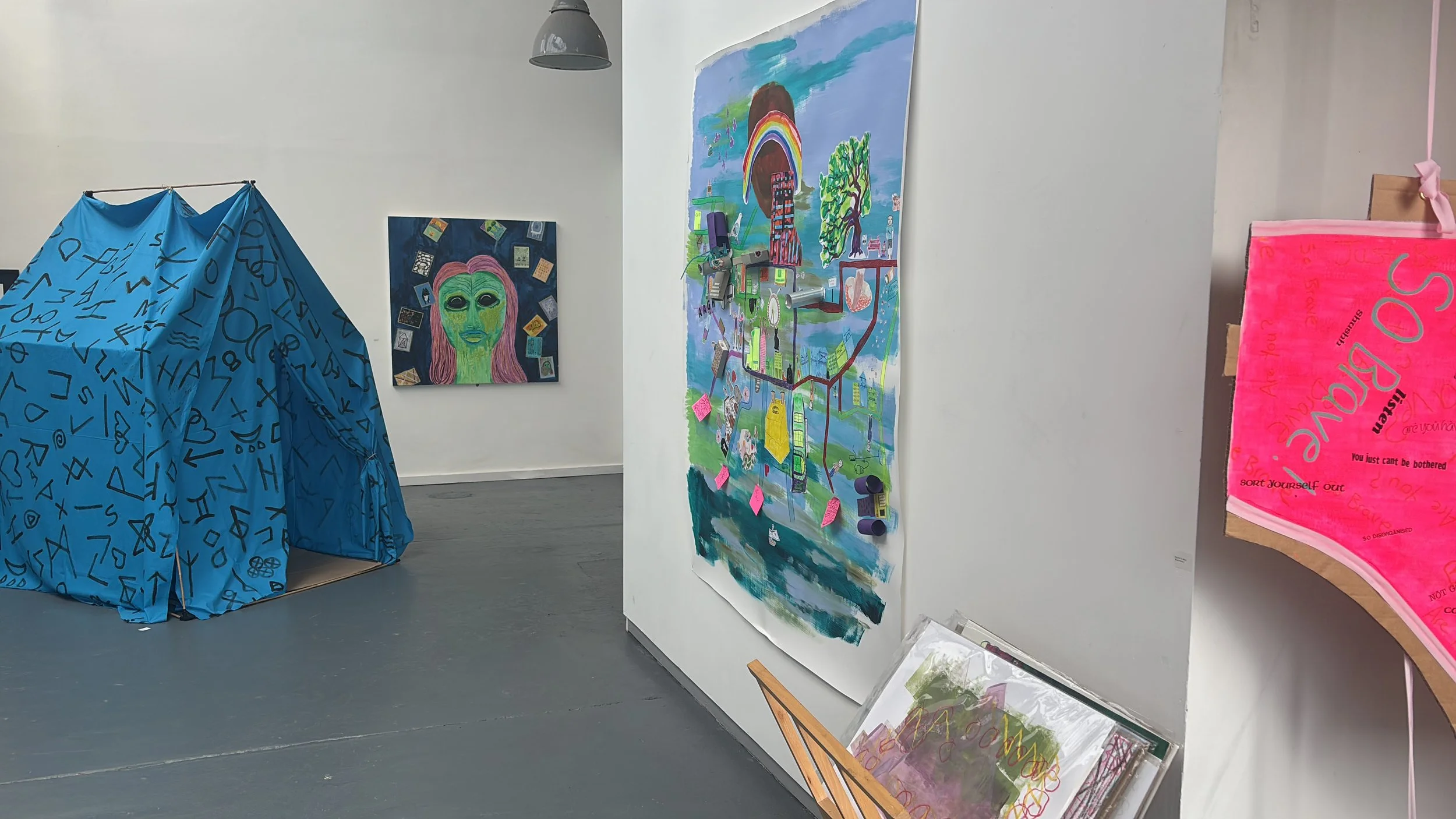 Art gallery with colorful paintings and a blue fabric installation with alphabet print.