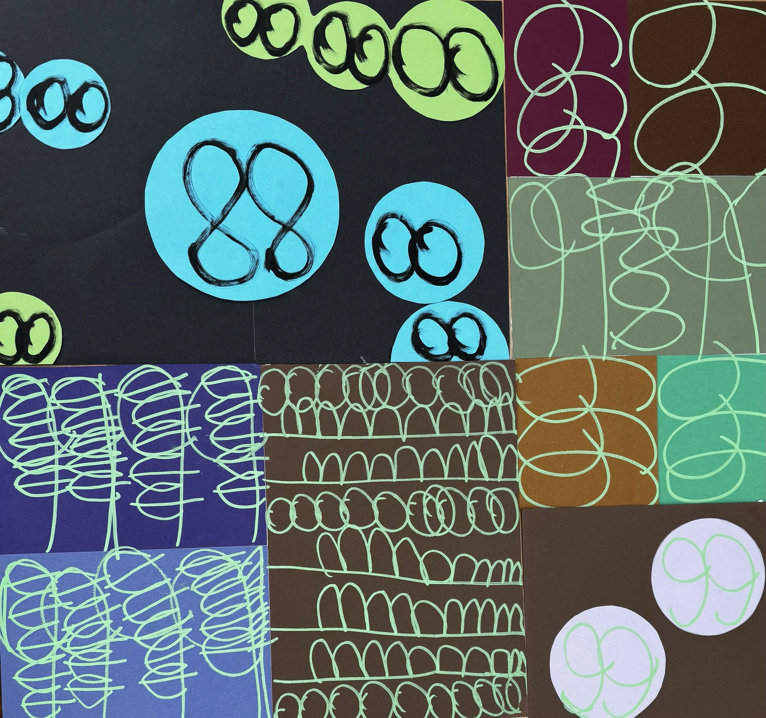 Assorted colorful paper circles and doodles arranged on a surface, featuring overlapping circles and squiggly lines in shades of blue, green, purple, brown, and gray.