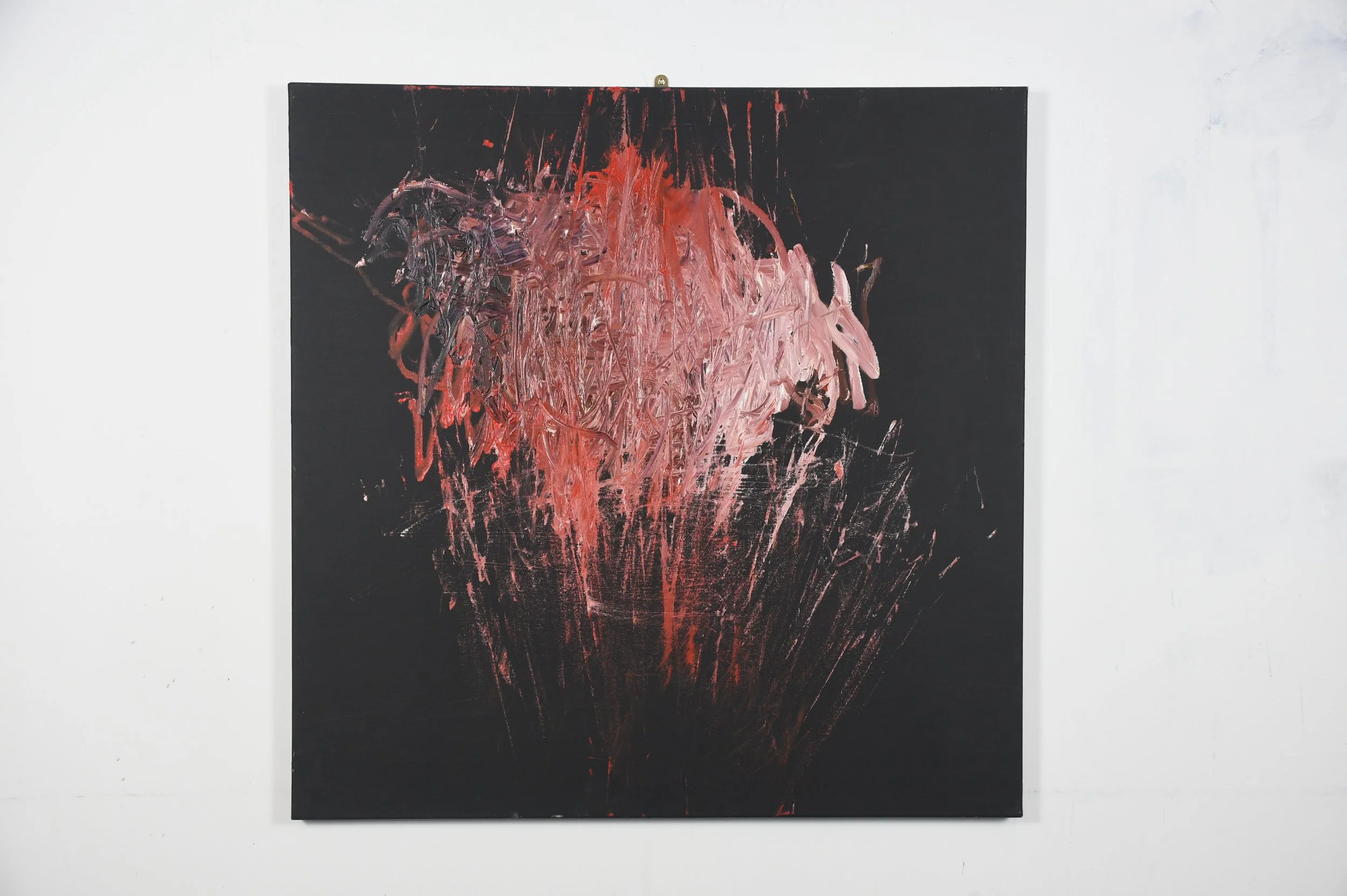 Abstract expressionist painting with red, pink, and black brushstrokes on a black background, mounted on a white wall.