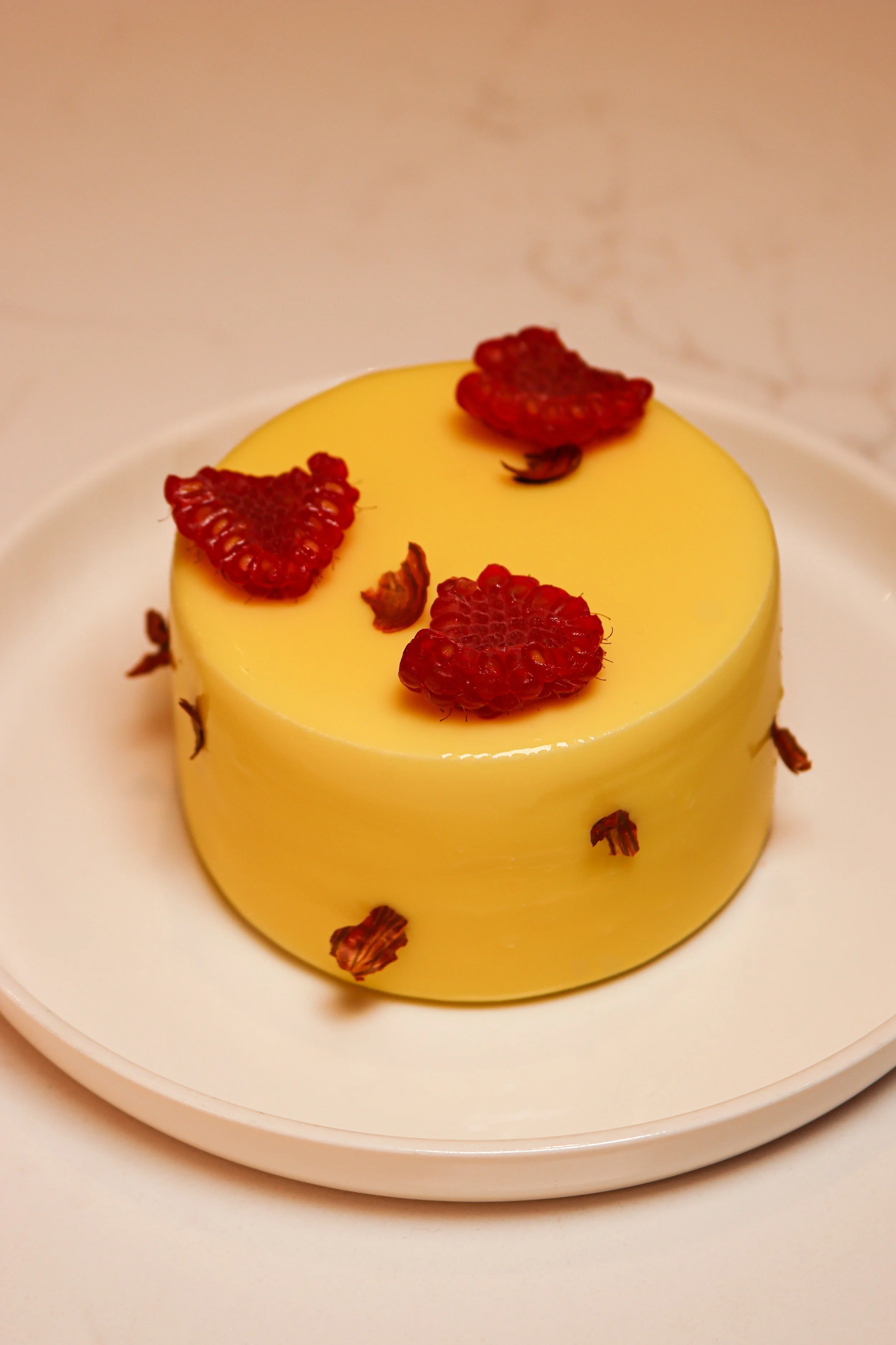 Gâteau élégant au citron décoré de framboises séchées et de petits morceaux de chocolat.