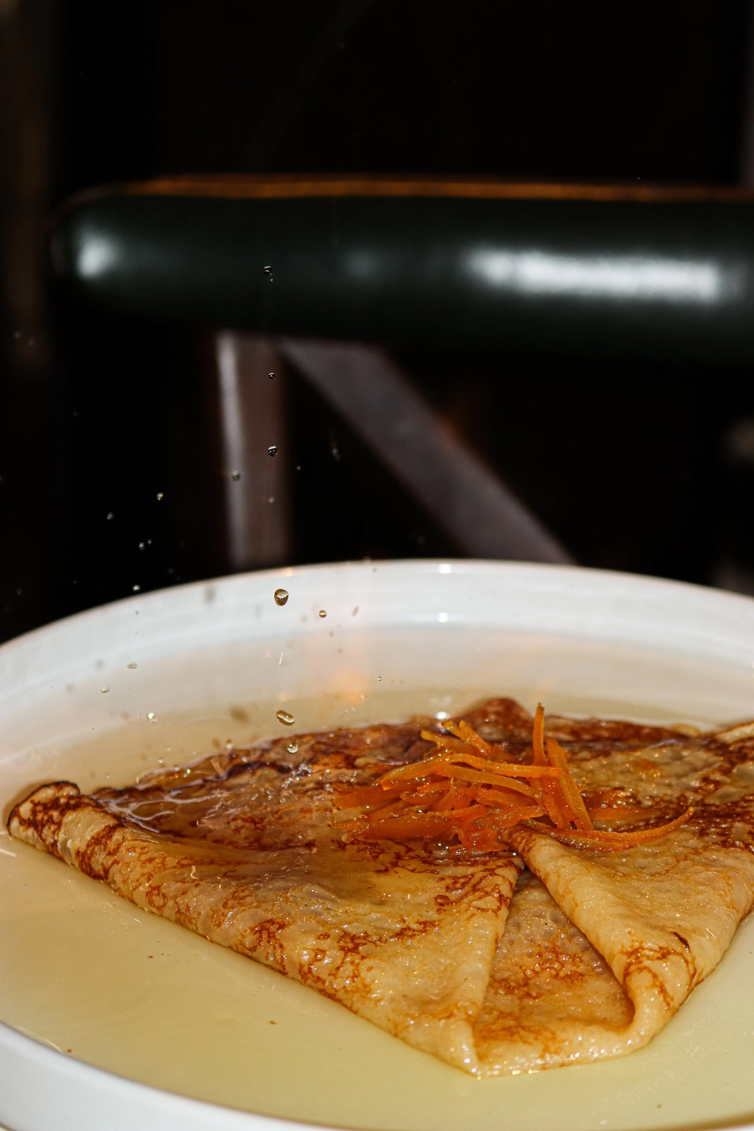 Crêpe dans une assiette, nappée de sauce avec des carottes râpées en garniture, vue de près.
