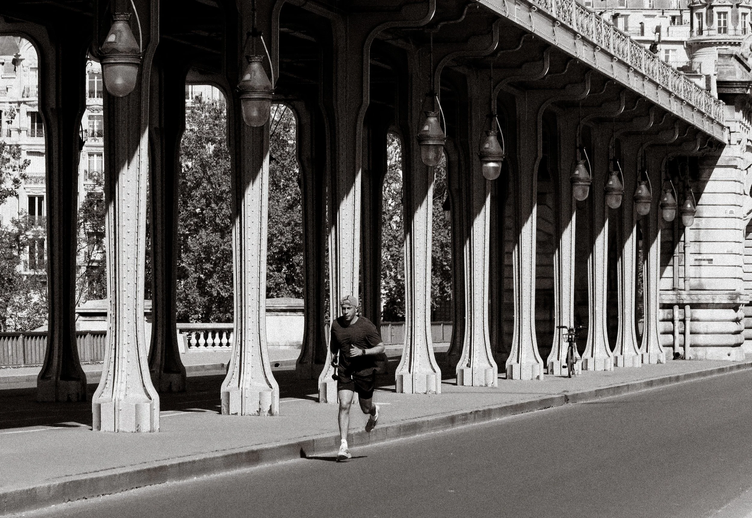 Photographie de sport: Un homme court seul sur le pont Bir Hakeim à Paris, le tout est en noir et blanc.