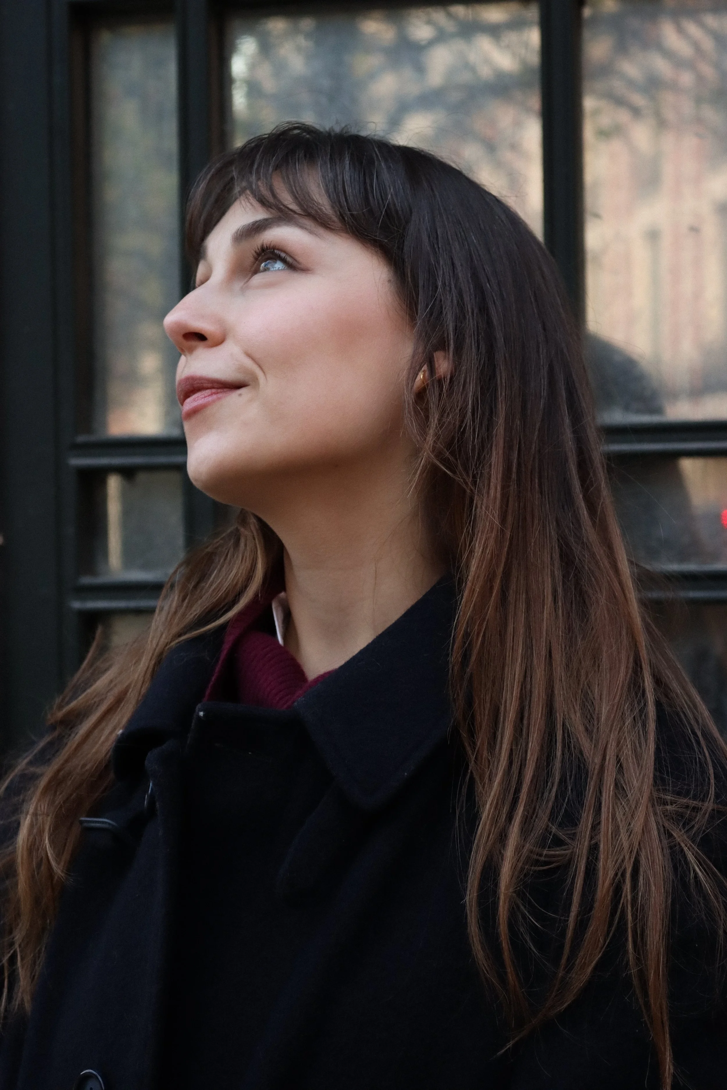 Photographie de portrait: une jeune femme avec cheveux longs bruns, regardant vers le haut, dans un décor parisien de la Place des Vosges devant le kiosque.