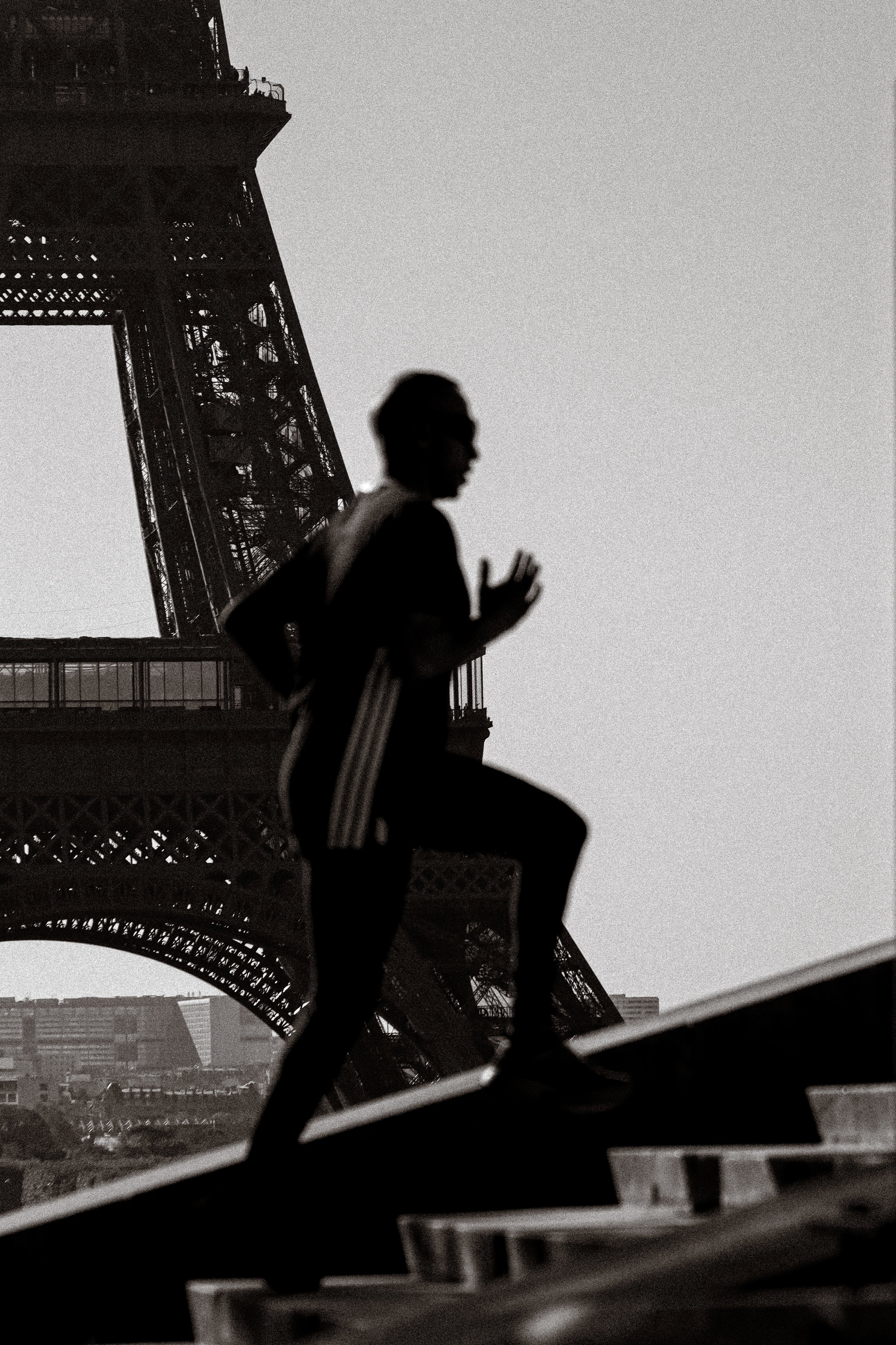 Photographie de sport : Silhouette d'une personne courant avec la tour Eiffel en arrière-plan, en noir et blanc.