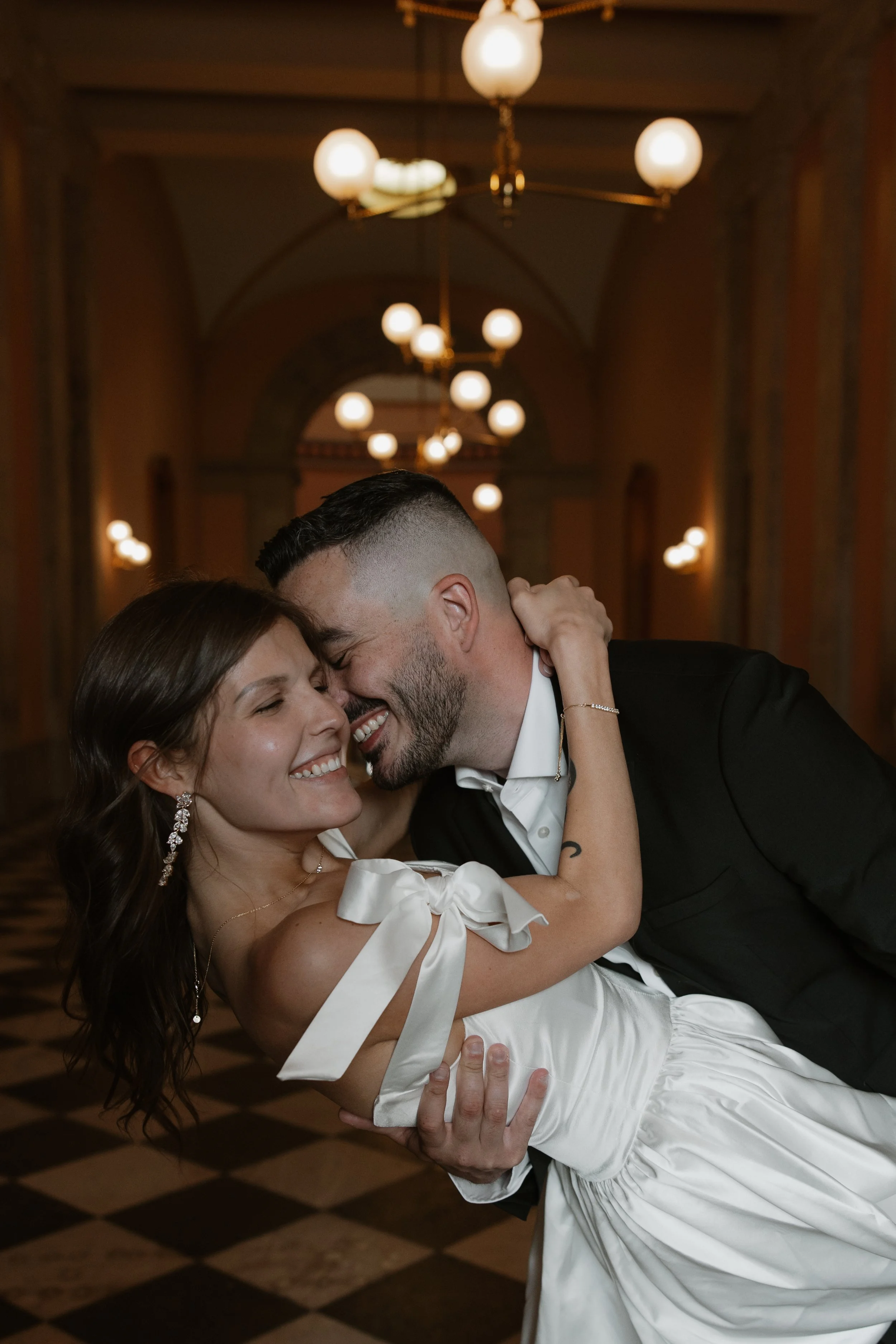 A happy couple sharing a dance, with the man dipping the woman in a grand, chandelier-lit hall.