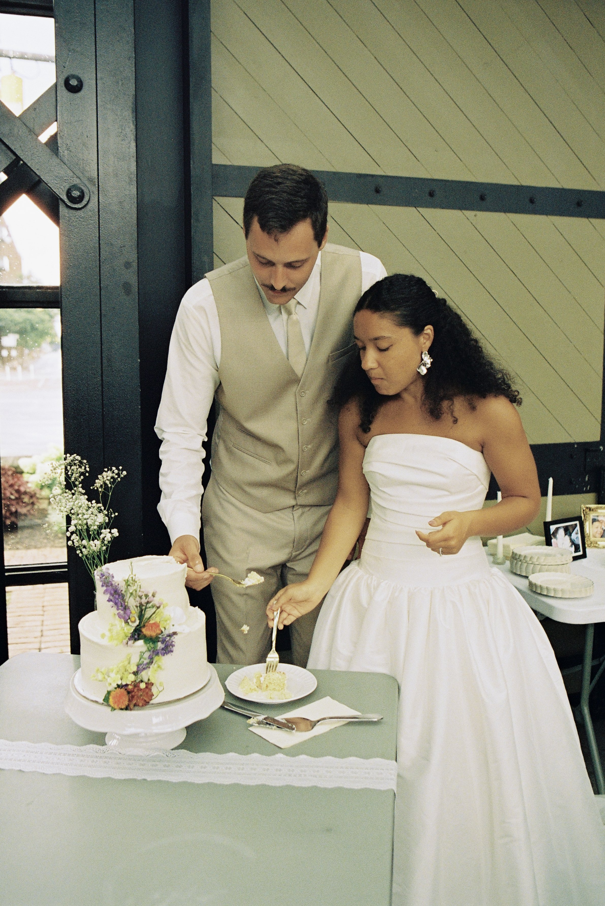 A bride and groom cutting a wedding cake together at their wedding reception.