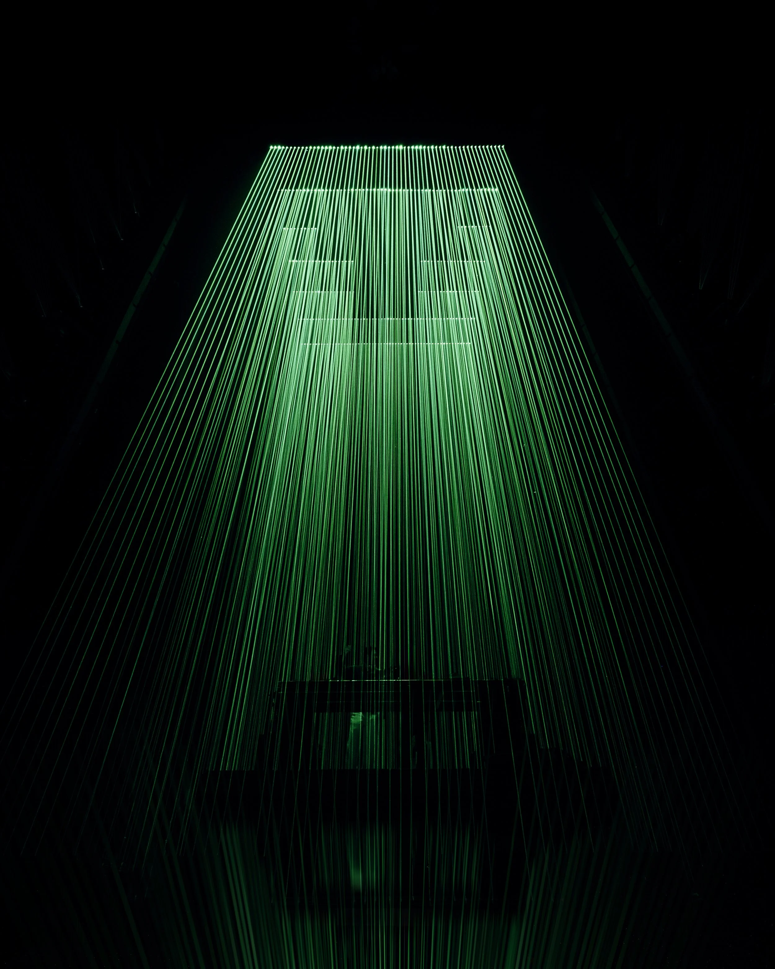 Vertical green lasers beams forming the shape of a house or building on a black background
