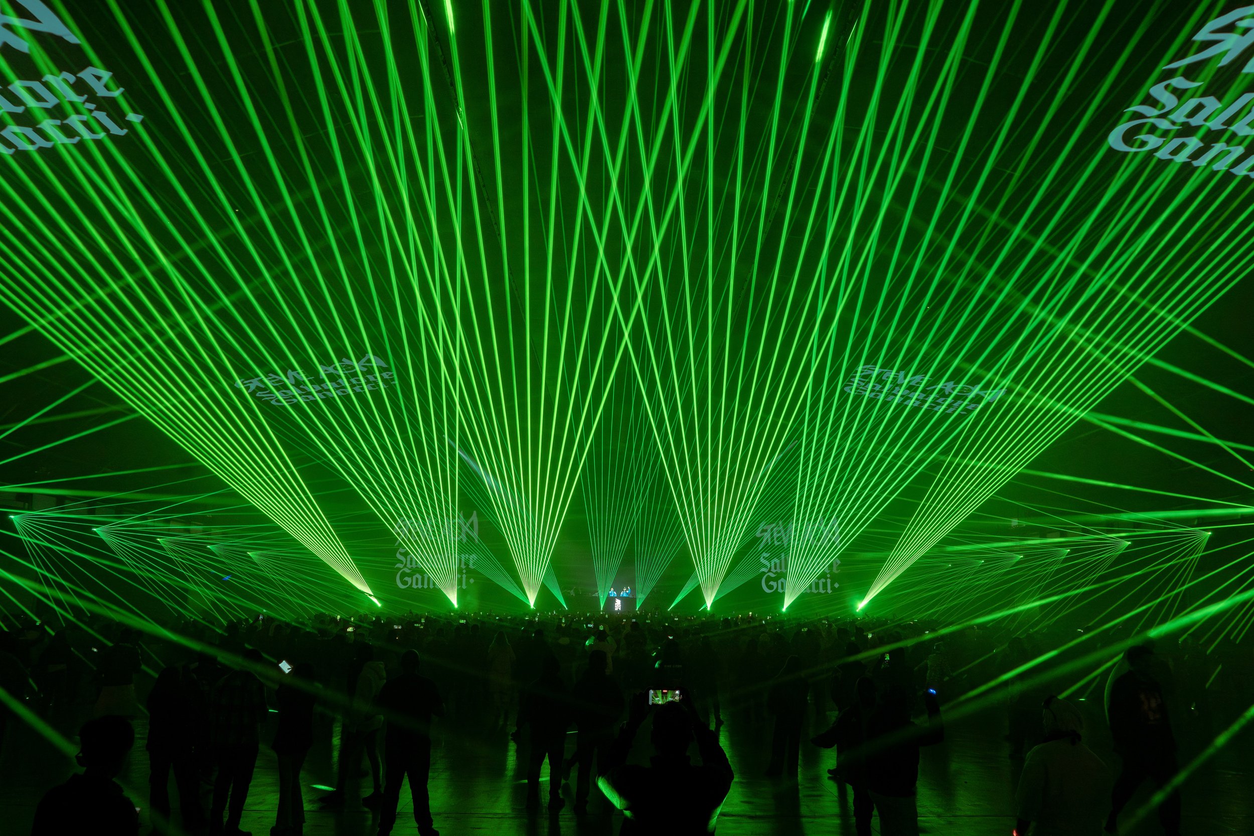 A concert or event with a large crowd and an elaborate green laser light display on stage.