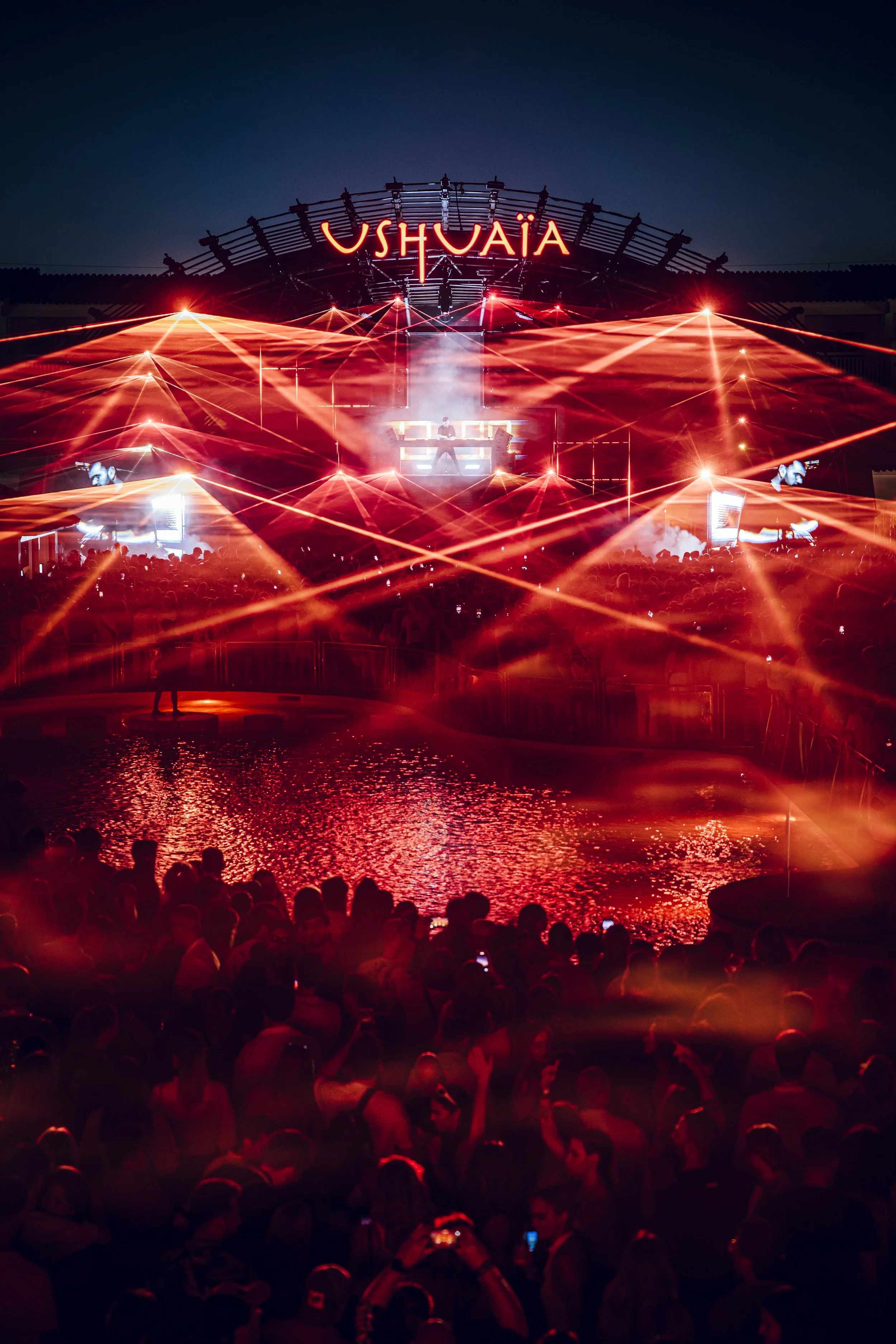 Nighttime concert scene at Ushuaïa with laser lights and a large crowd.