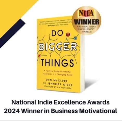 Book titled 'Do Bigger Things' by Dan McClure and Jinner Wilde, awarded the NEIA National Indie Excellence Award, 2024 winner in Business Motivational, displayed upright with a yellow cover and black and white text.