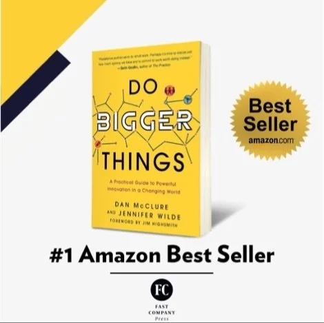 Book titled "Do Bigger Things" by Dan McClure and Jennifer Wilde with a yellow cover, surrounded by promotional tags indicating it is a best seller on Amazon and the number one Amazon best seller.