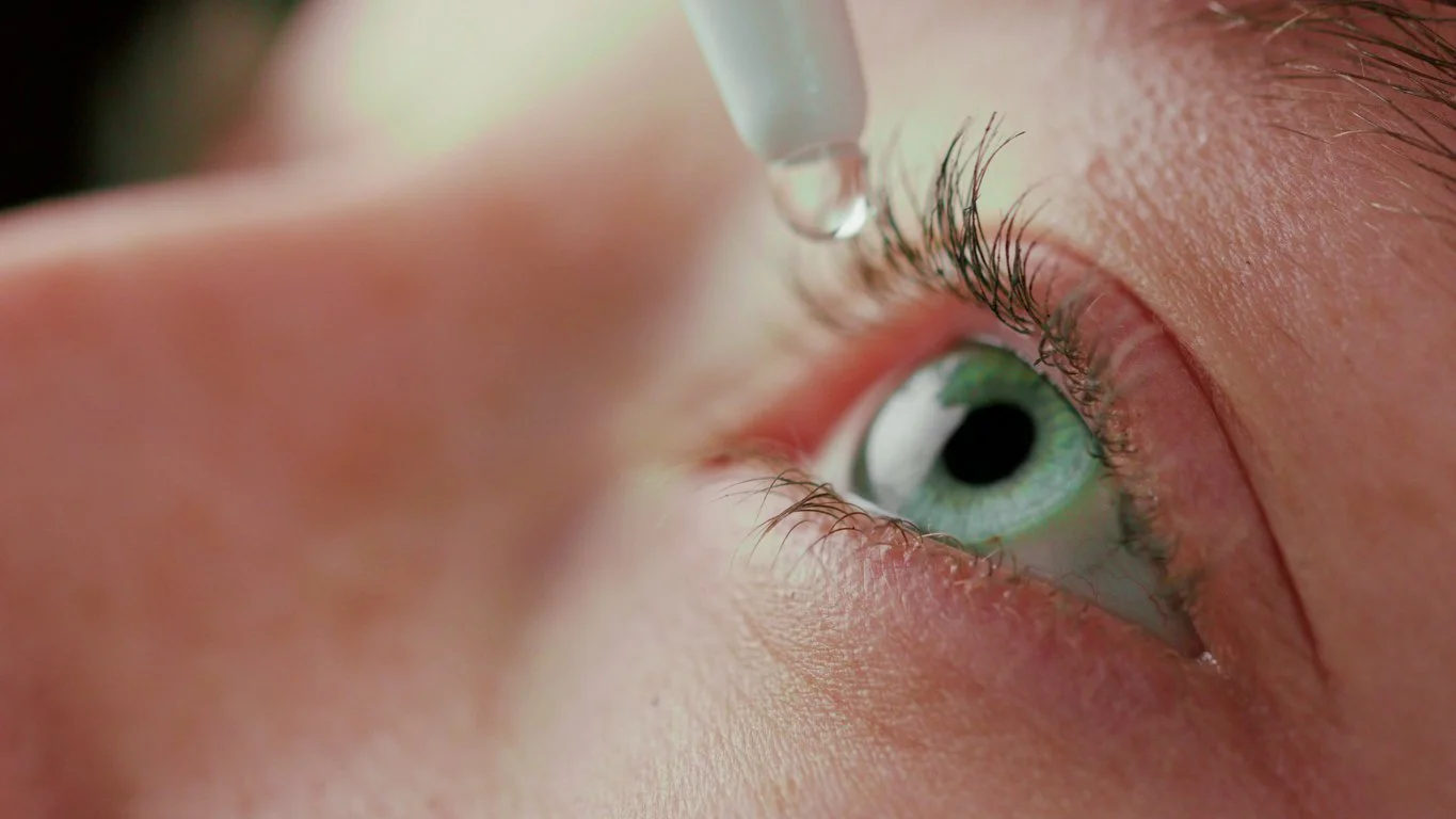 Close-up of an eye being examined with a medical instrument, showing the detailed lashes and iris.