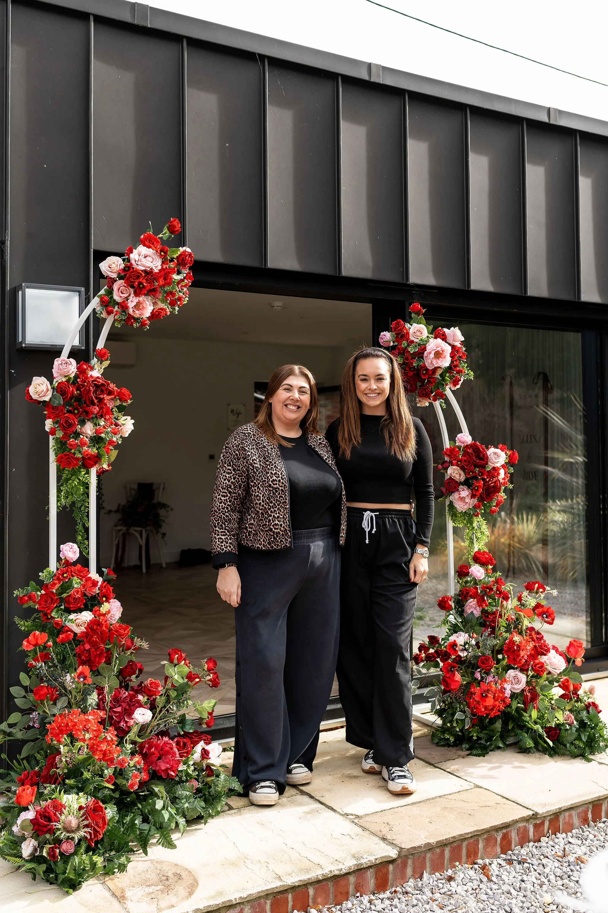 Sophia and Gemma standing outsider Little Massingham Manor under a beautiful rose arch they created.