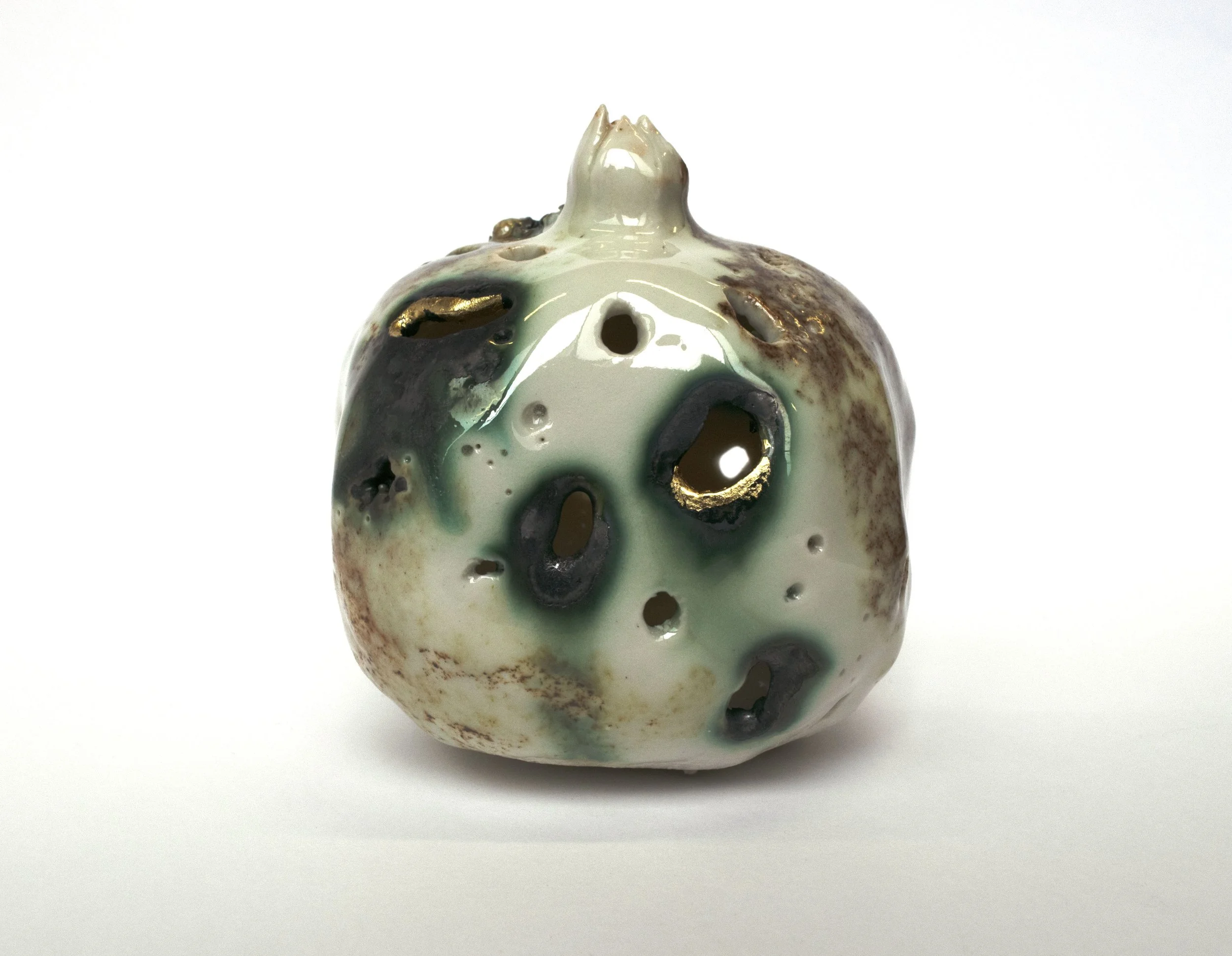 Ceramic vase with irregular holes, glazed in a mix of cream, green, brown, and black colors with gold accents, placed on a white background.