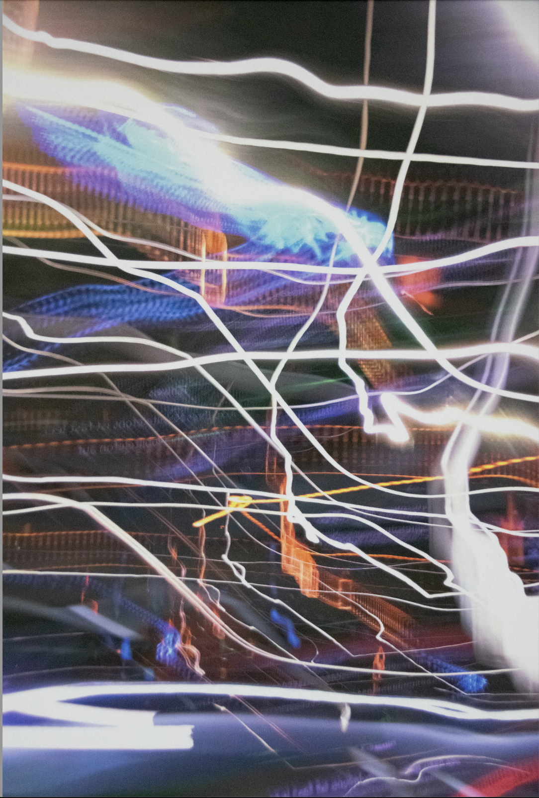 Abstract photo of illuminated streaks of white, blue, purple, and orange light against a dark background, creating a dynamic, chaotic pattern.