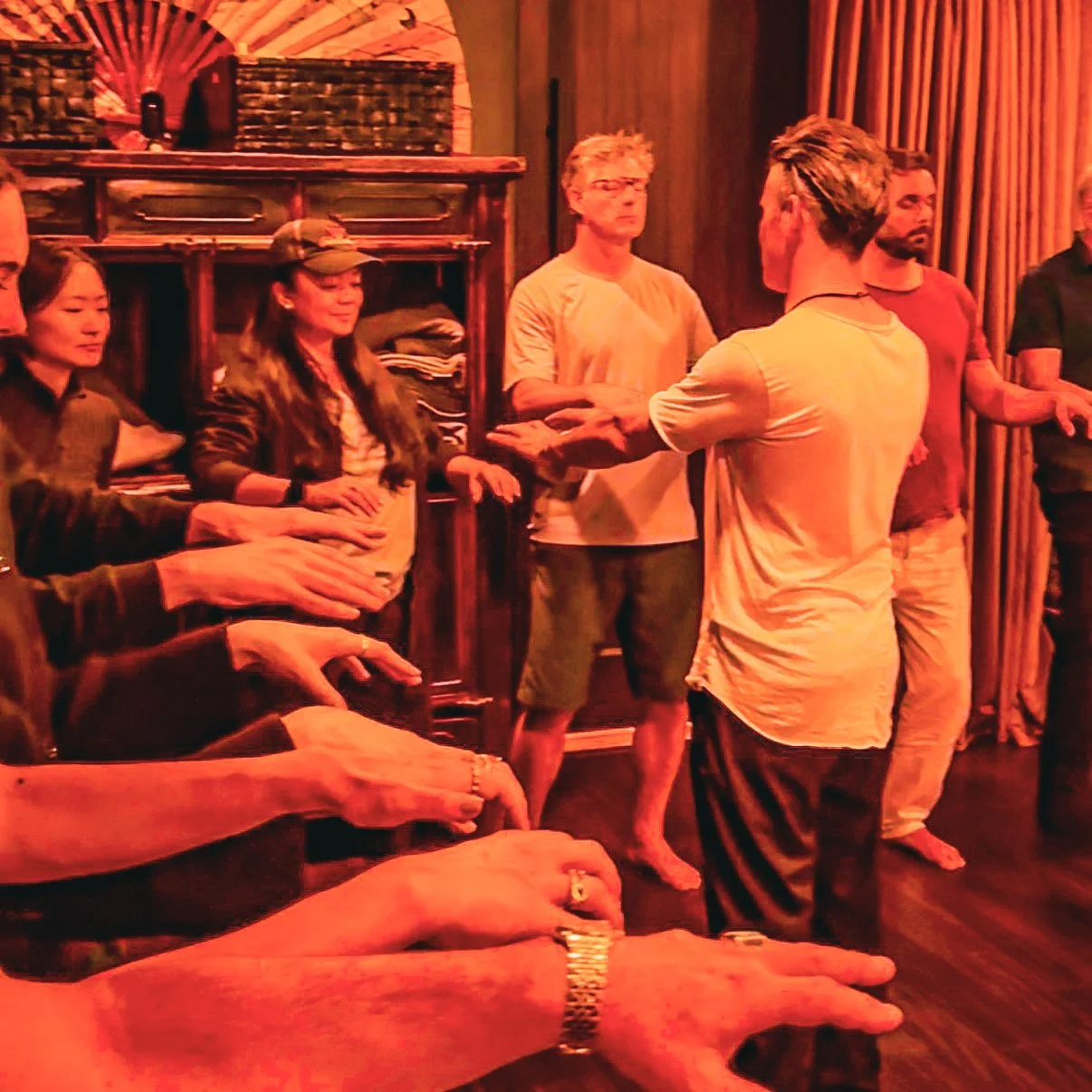 Group of people engaged in a Reiki healing session, with hands extended towards a person in the center.