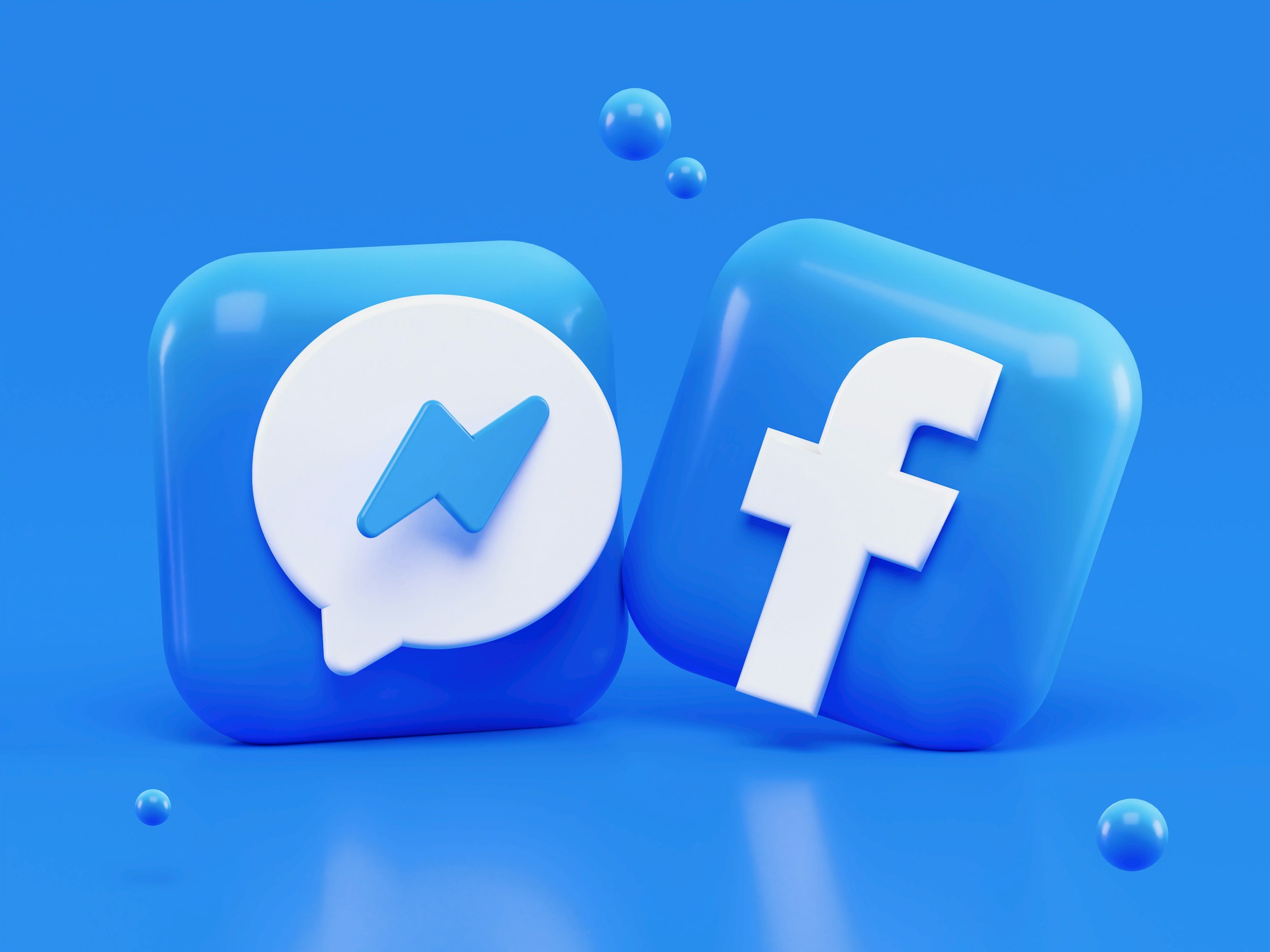 Facebook and Messenger logos in blue 3D icons with floating spheres against a blue background.