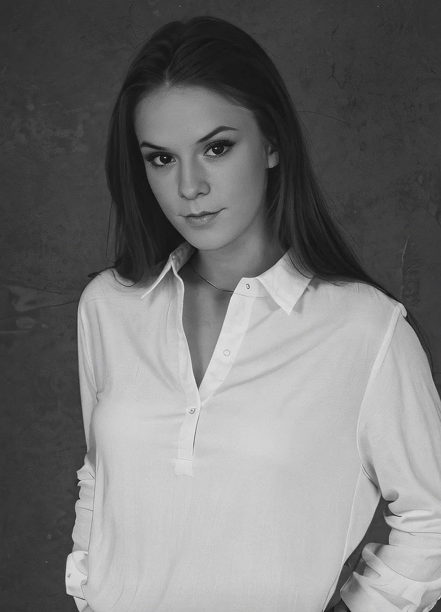 Black and white portrait of a woman in a white blouse with a neutral expression.