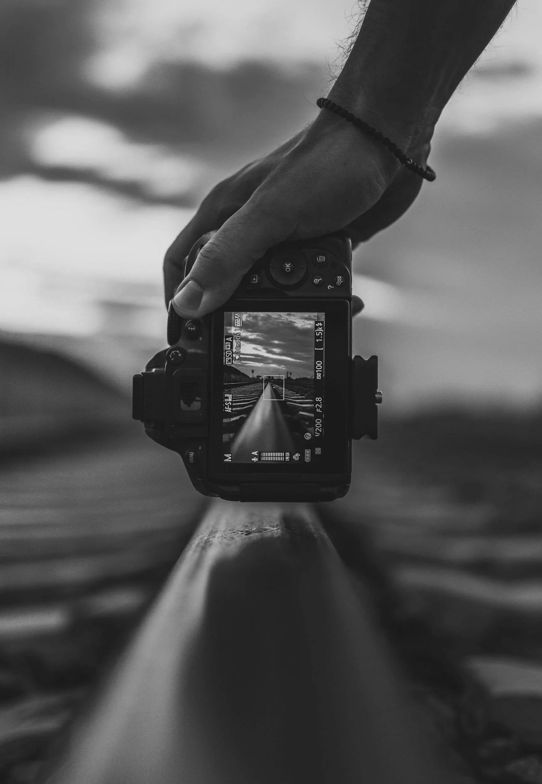 Black and white image of a camera filming a person's hand on a keyboard.