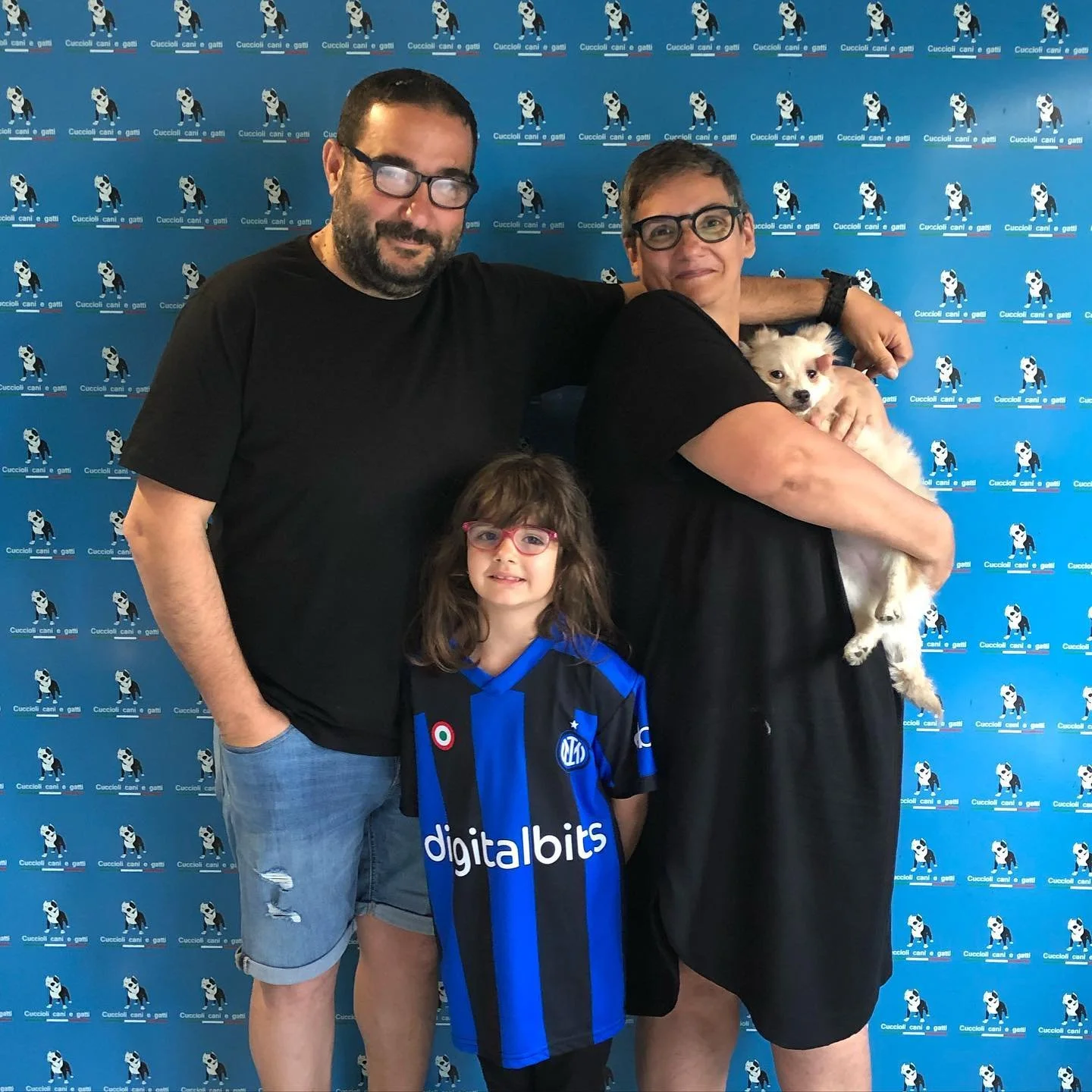 Tre persone e un cane, sfondo con motivo di cani disegnati e parole 'Cuccioli, cani e gatti'.