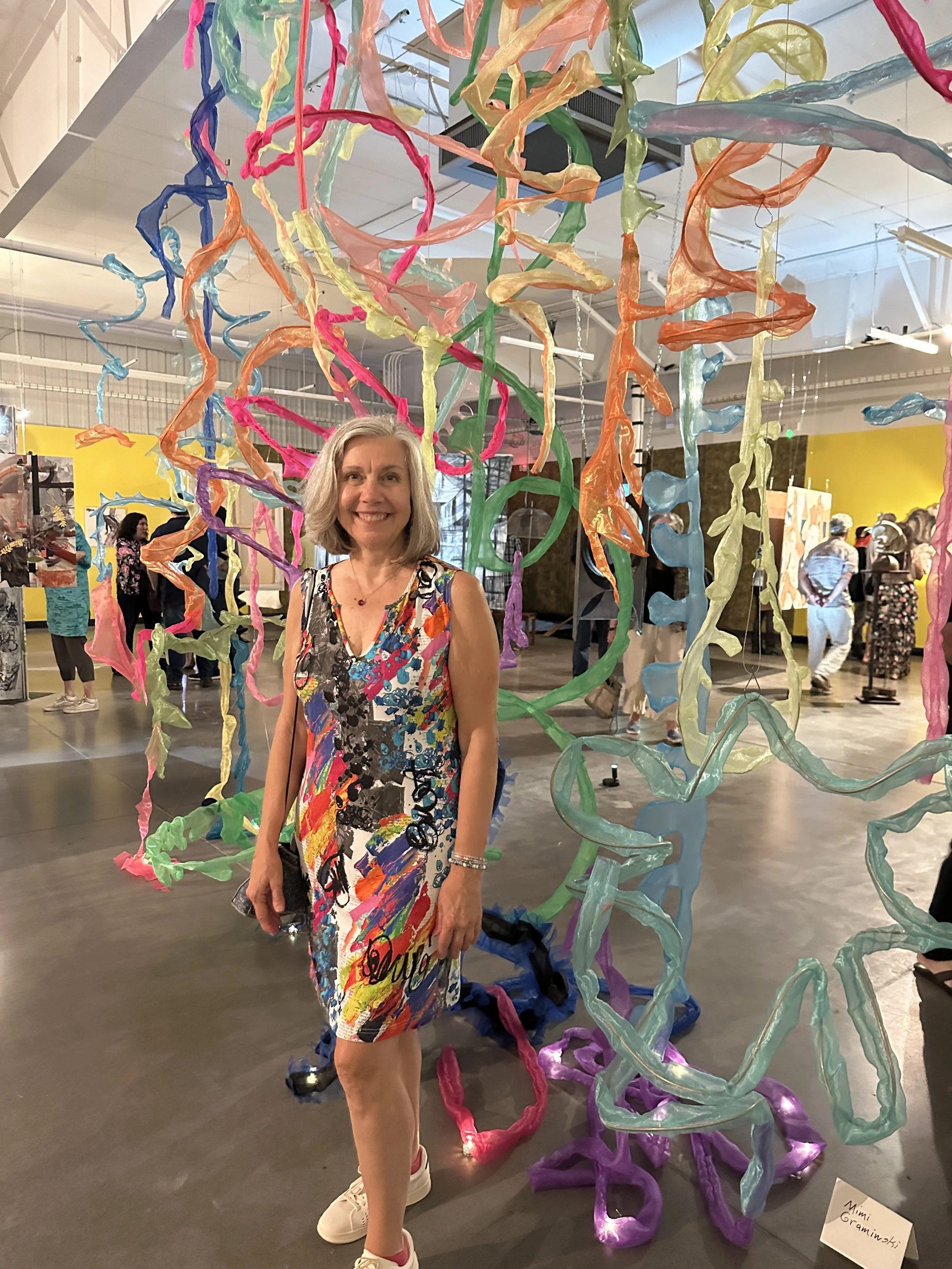 Artist Mimi Graminski standing within her colorful site-specific installation at Site Seen's Of Frame and Fallow exhibition inside a former Dollar General building in Esopus, New York.