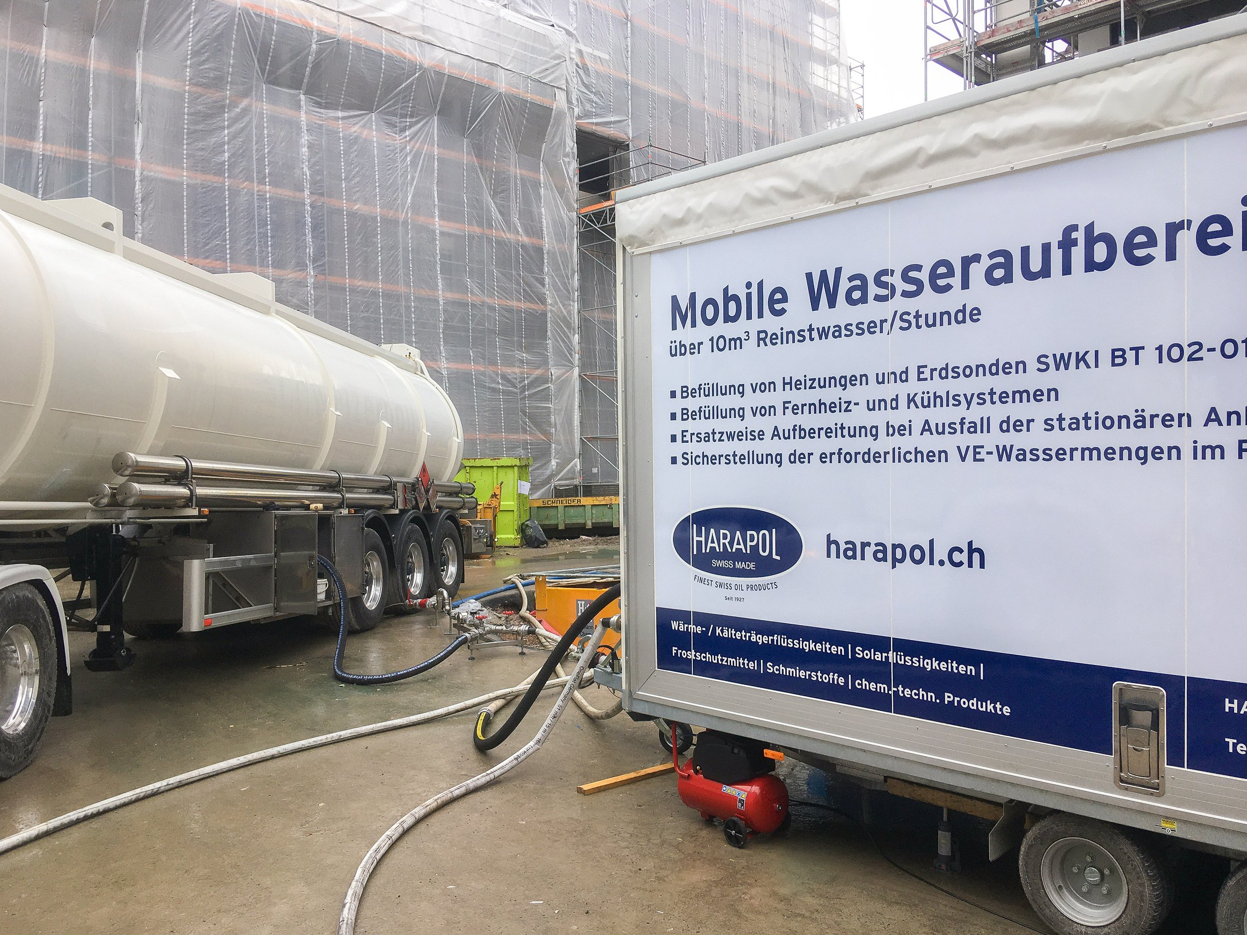 Auf einer Baustelle befindet sich eine mobile Wasseraufbereitungsanlage mit einem Tankwagen und einer Technikstation, die Wasser für Heizsysteme und Kühlsysteme aufbereitet.