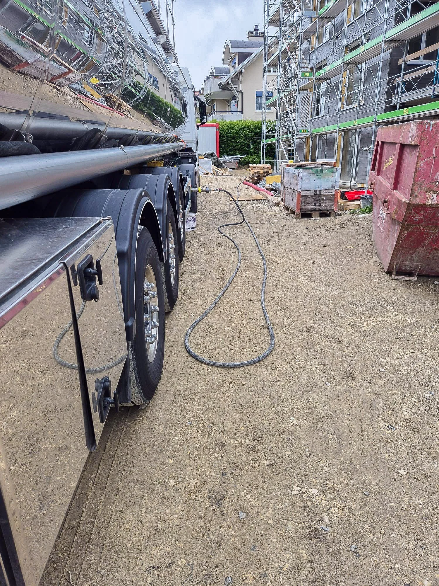 Baustelle mit Baugerät, Container, Absperrungen und Baugerüsten bei mehrstöckigem Bauvorhaben.