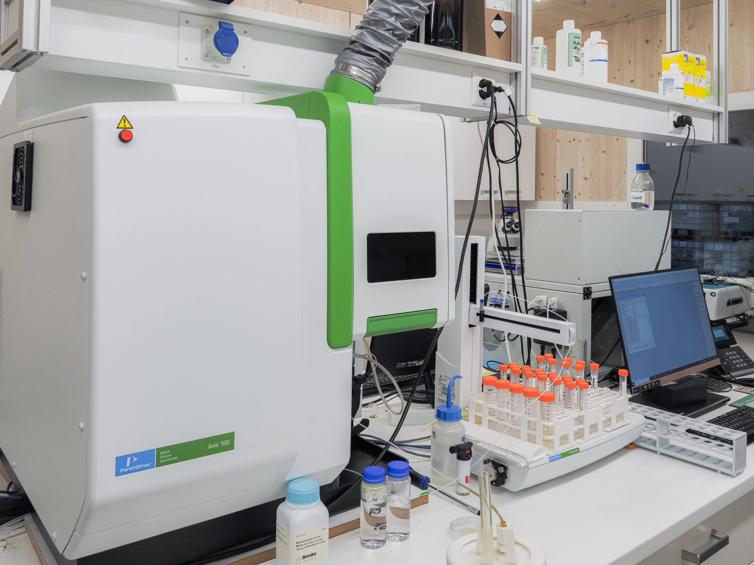 Laborarbeitsplatz mit chemischer Analysestation, Reagenzgläser, Computer und wissenschaftliche Geräte.