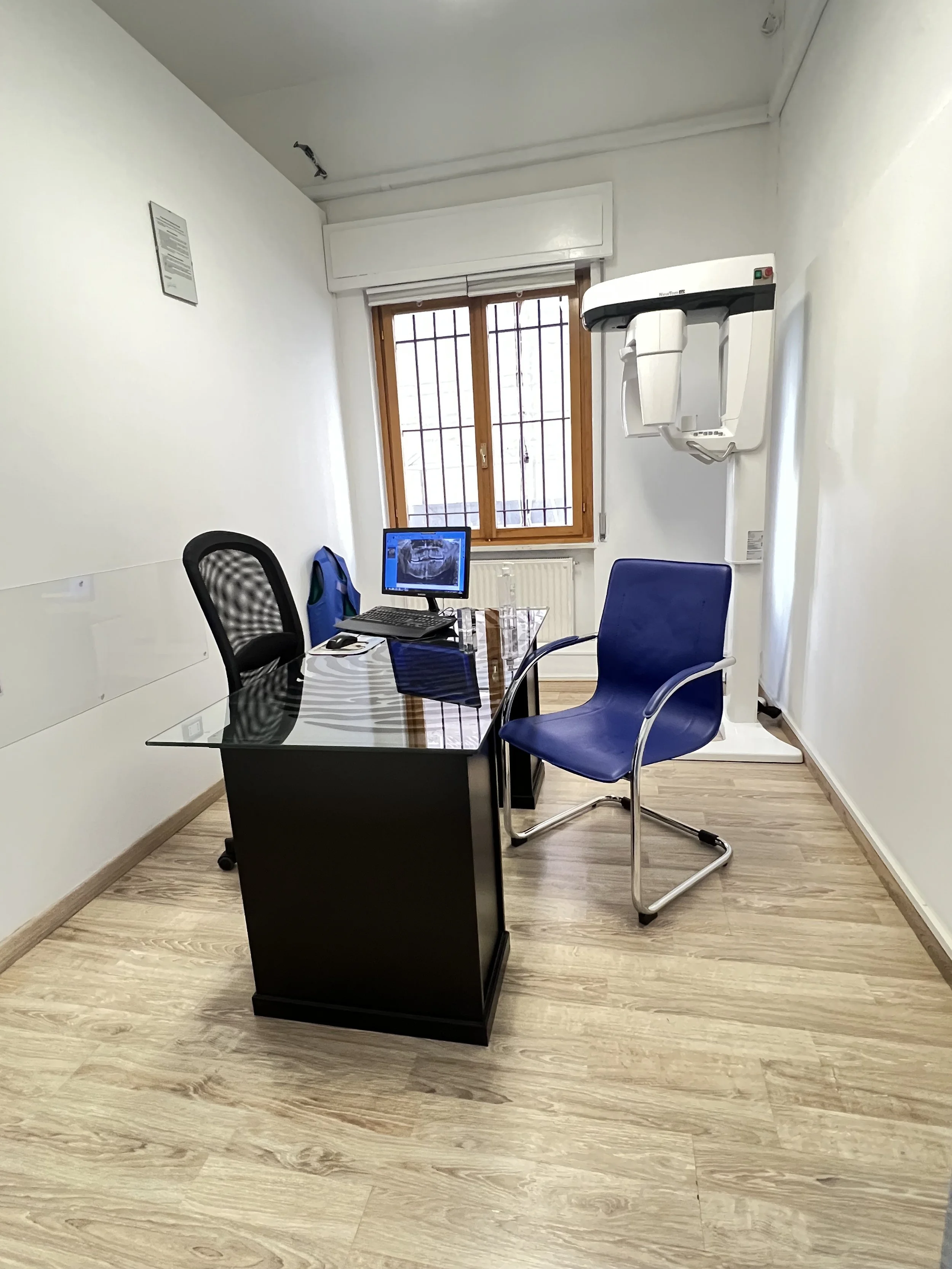 Stanza medica con scrivania, due sedie, monitor e macchinario odontoiatrico