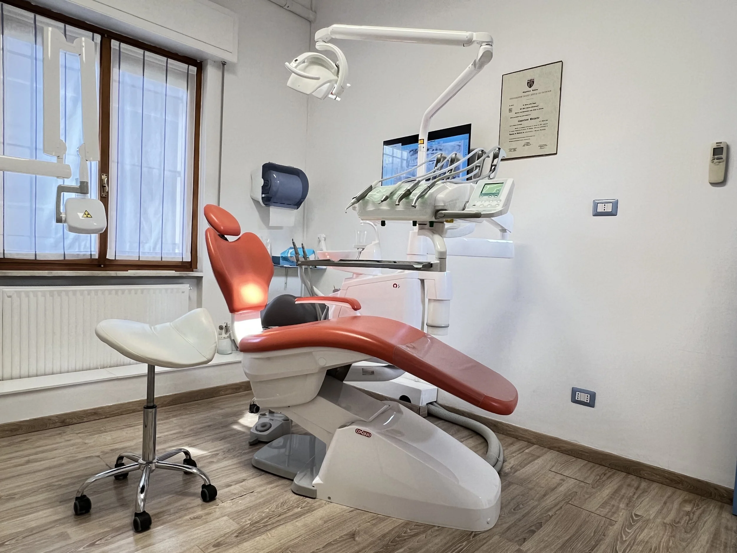Sedia da dentista rossa in uno studio dentistico con attrezzature e monitor.