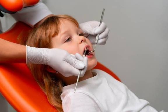 Bambina seduta sulla sedia del dentista durante un controllo dentistico.