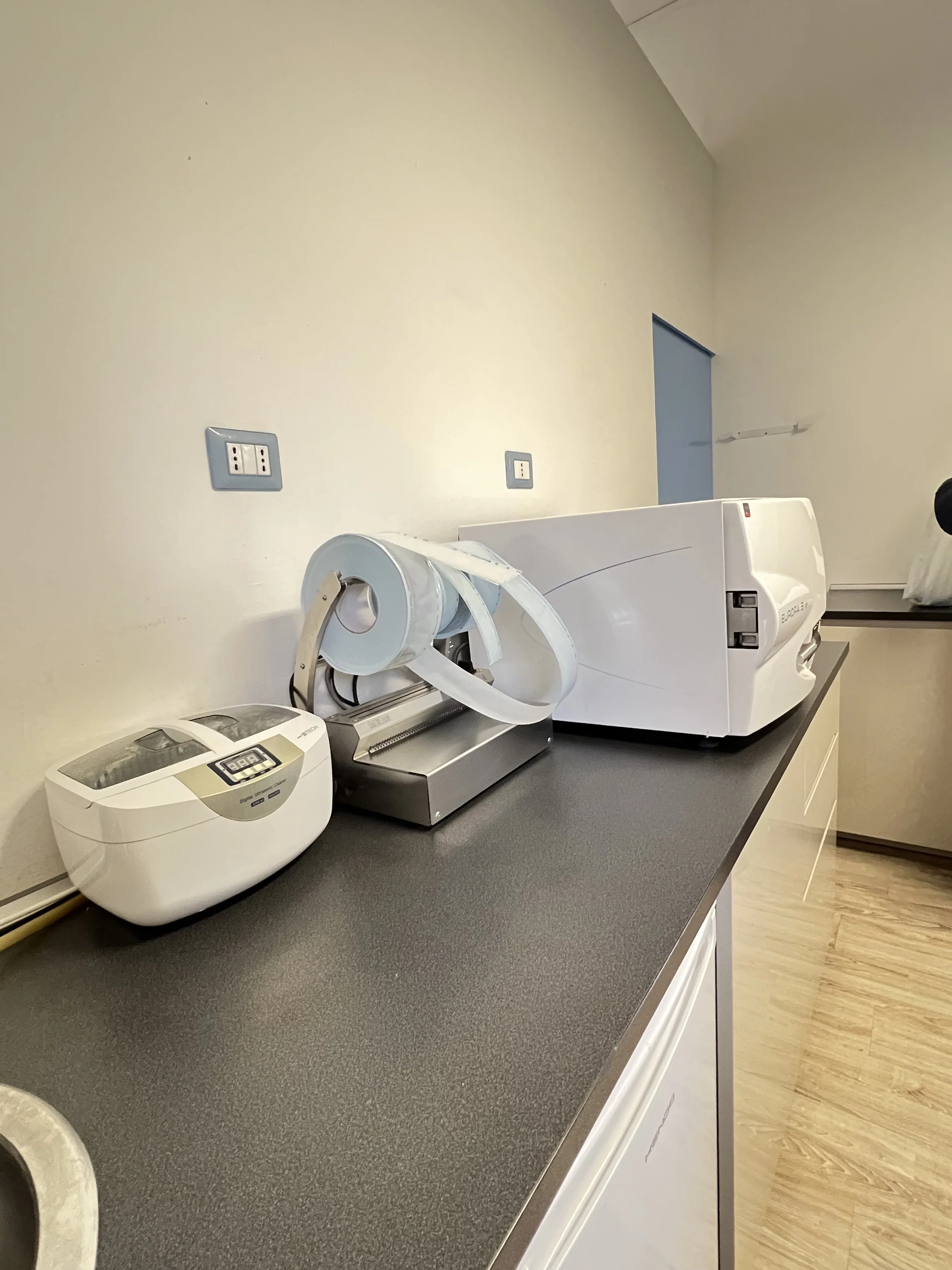 Attrezzature mediche su un piano di lavoro, inclusi dispositivi di radiografia e una stampante medica.