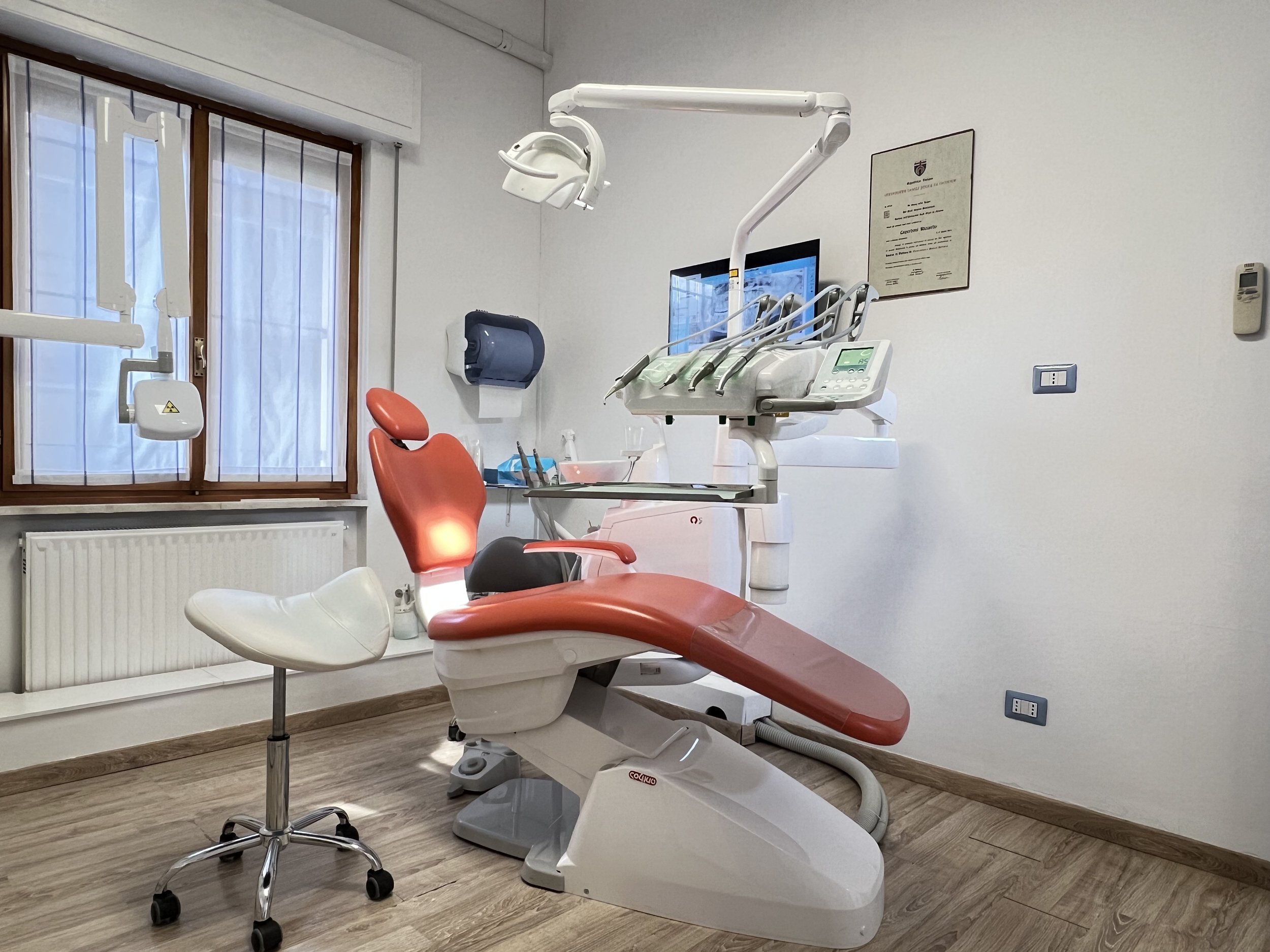 Studio dentistico con poltrona rossa e attrezzature odontoiatriche