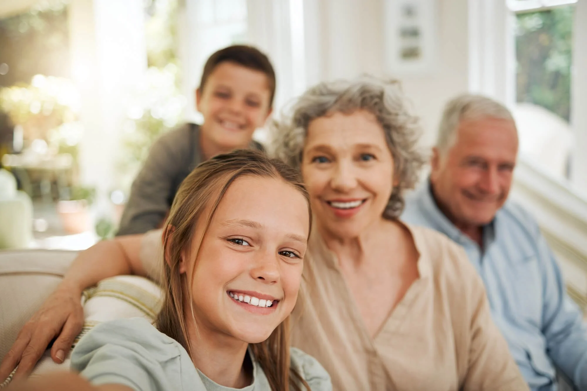 Family smiling together in a bright living room, taking a selfie.