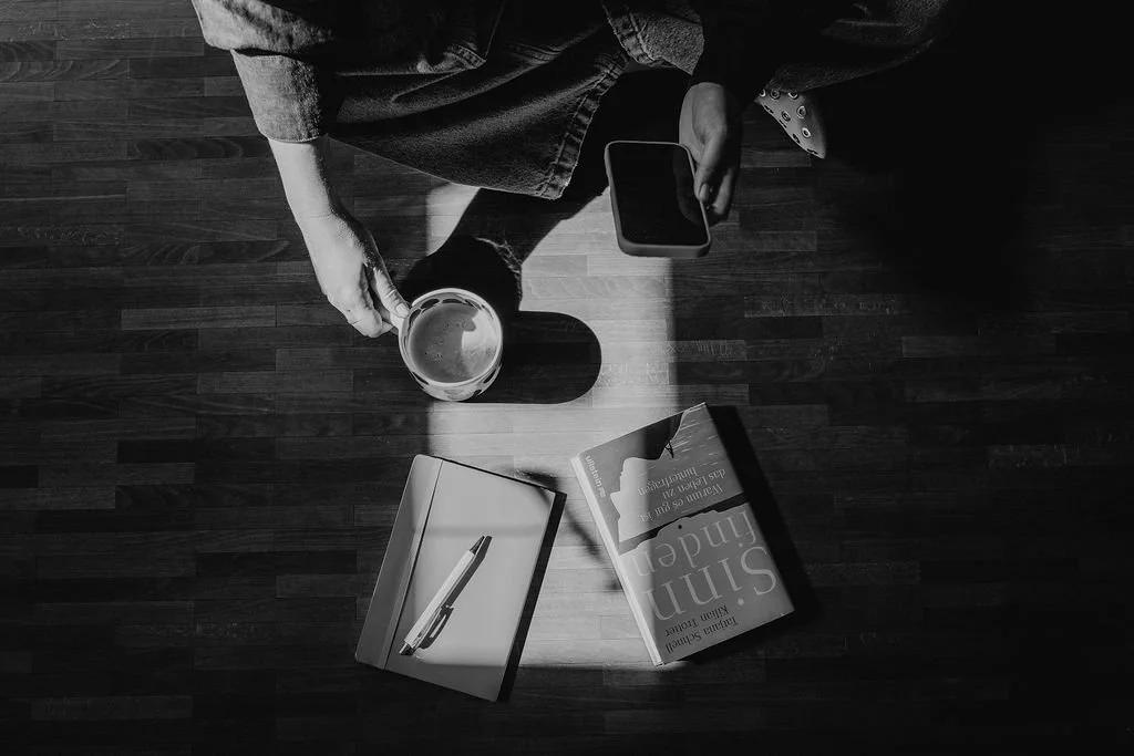 Vogelperspektive auf Arbeitsplatz mit Tee, Notizbuch und Büchern - Ruhe und Reflexion