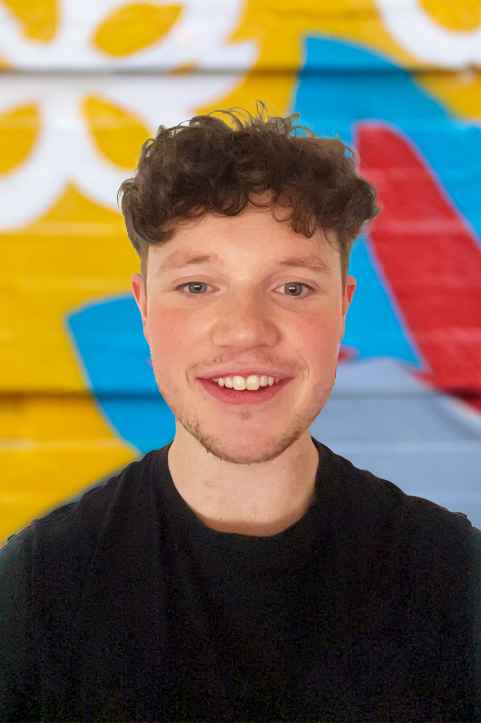 A young man with curly hair smiling in front of a colorful, abstract background.