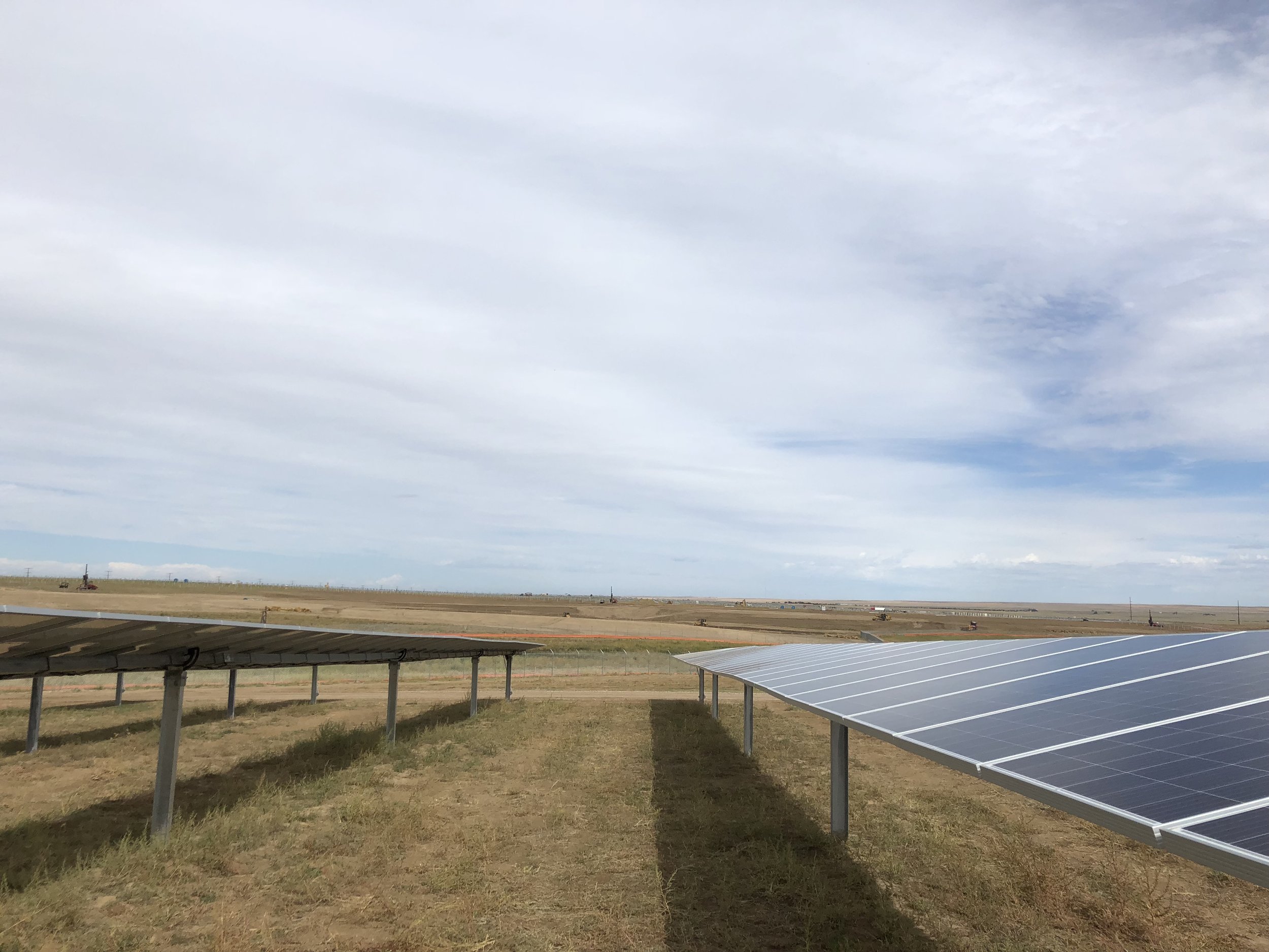 Solar panels installed in an open field under a partly cloudy sky in Colorado by Revamp Engineering solar power and repowering