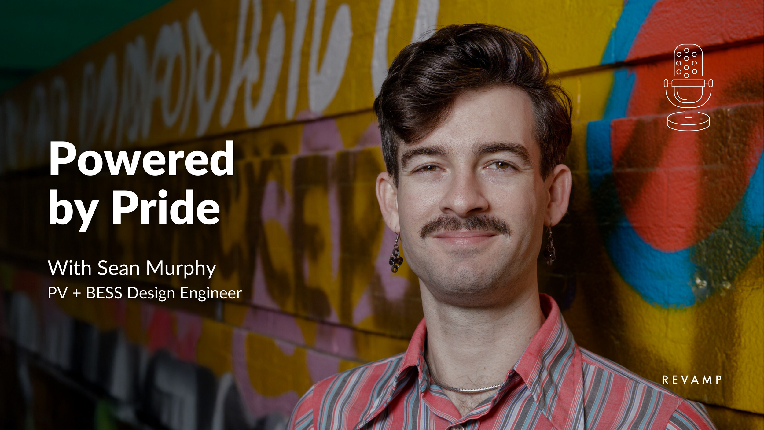 A young man with a mustache and earrings smiling in front of a colorful graffiti wall.